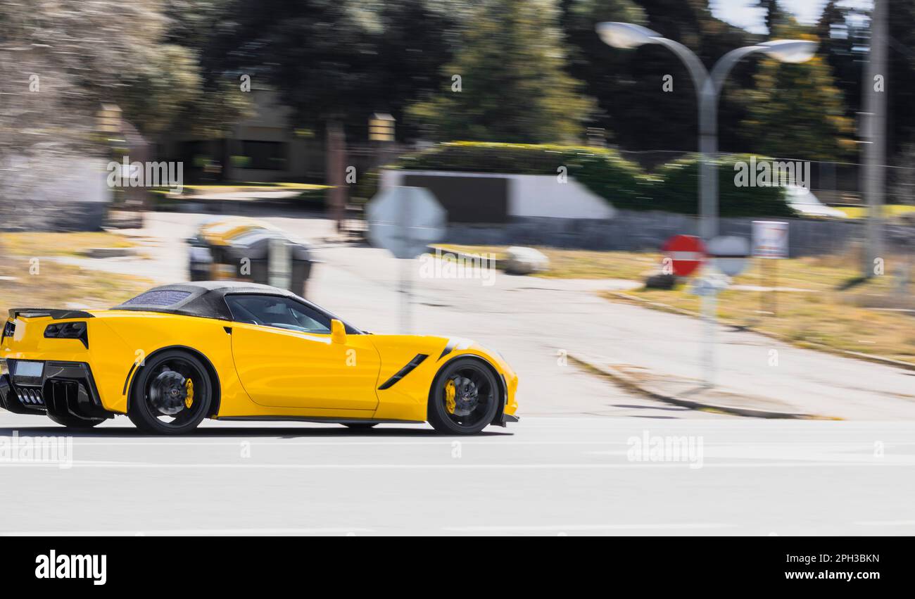 Voiture de sport de luxe jaune, conduite à grande vitesse sur une route urbaine pendant la journée, balayage. Banque D'Images