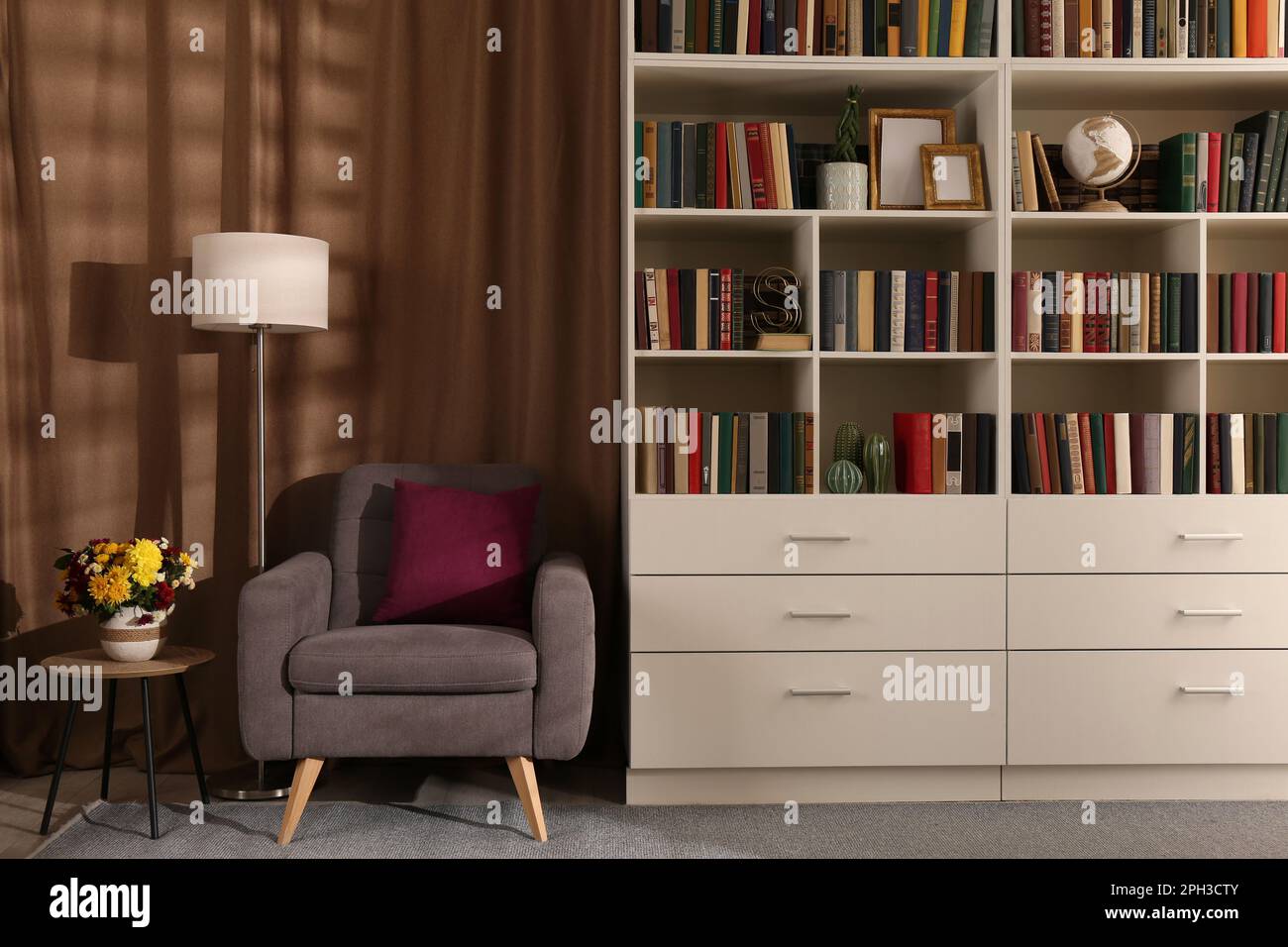 Intérieur confortable de la bibliothèque avec fauteuil confortable,  lampadaire et collection de livres sur les étagères Photo Stock - Alamy