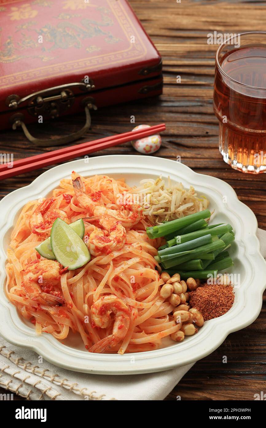 Assiette thaïlandaise traditionnelle de nouilles de riz sautées, crevettes et légumes sur une table en bois Banque D'Images
