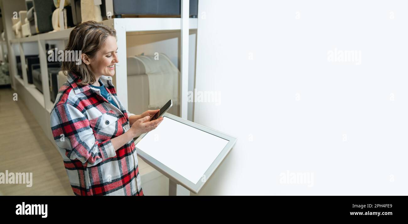 La femme utilise le kiosque en libre-service dans le magasin. Banque D'Images