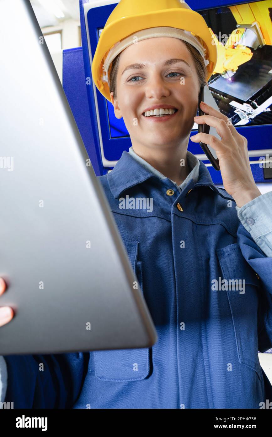 Femme ingénieur avec une tablette numérique et un téléphone dans une usine intelligente. Gros plan. Photo de haute qualité Banque D'Images