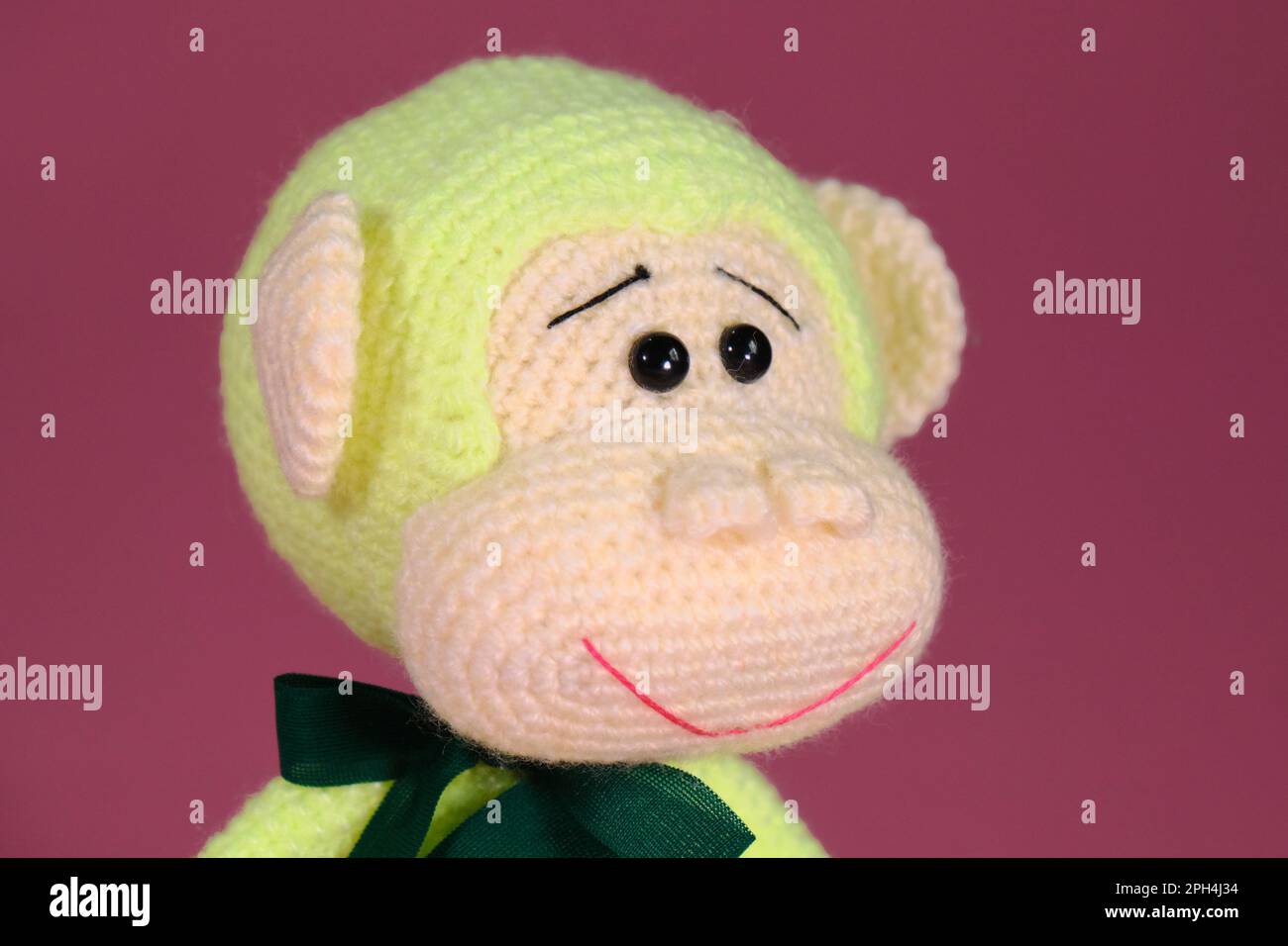 Jouet bricolage doux en coton naturel et laine. Joli petit singe avec noeud sur le cou crocheté, art fait à la main Amigurumi un singe vert avec de grandes oreilles Banque D'Images