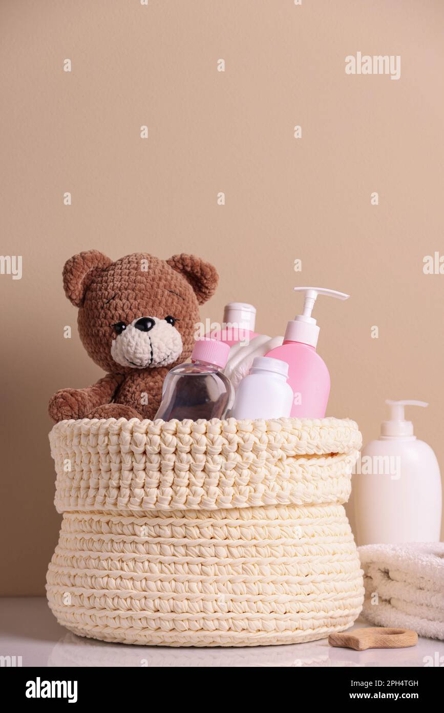 Panier tricoté avec produits cosmétiques pour bébés et ours en peluche sur  table blanche sur fond beige Photo Stock - Alamy