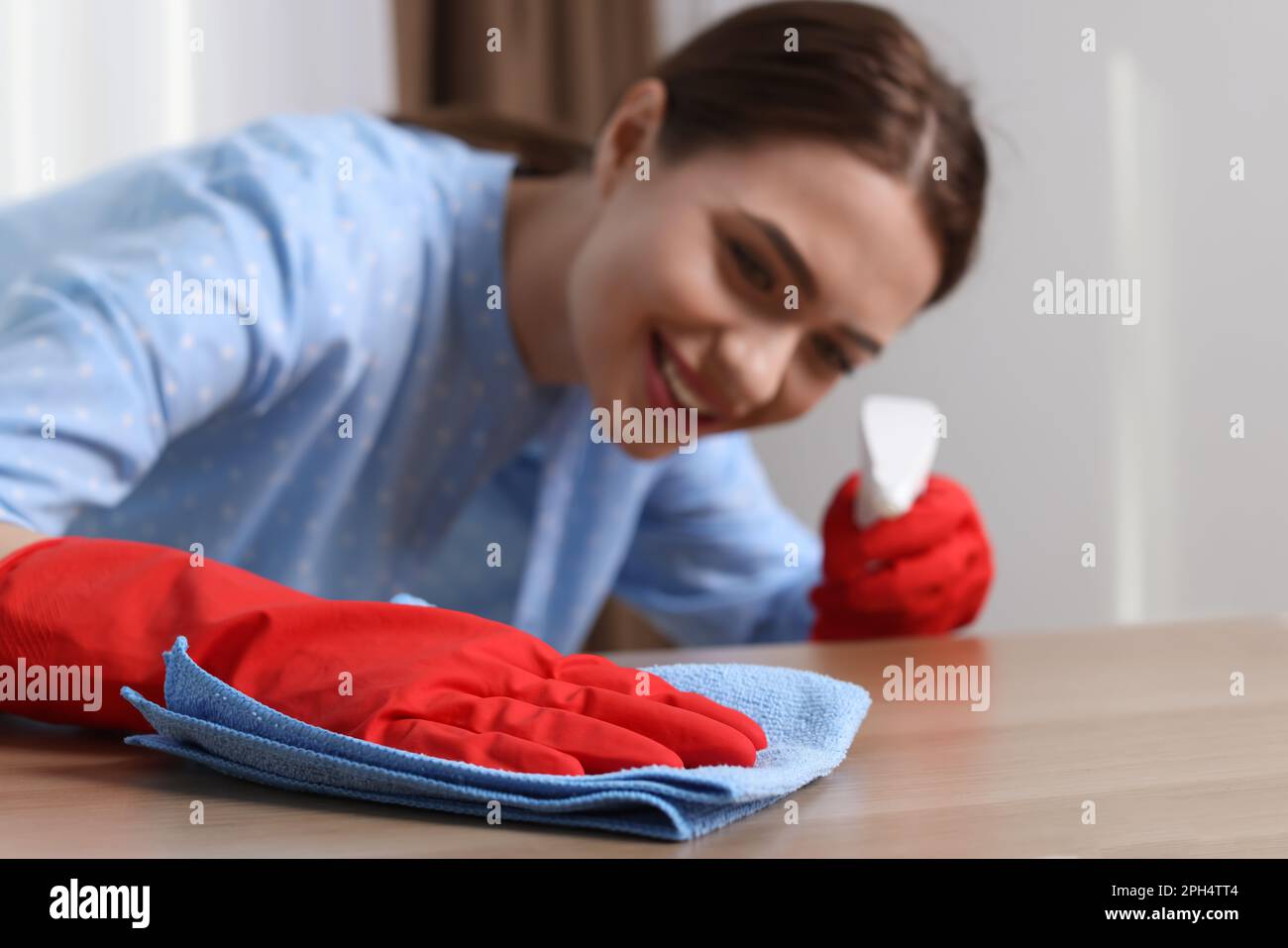 Une jeune femme nettoie une table en bois avec un chiffon à la maison, se concentre sur la main Banque D'Images