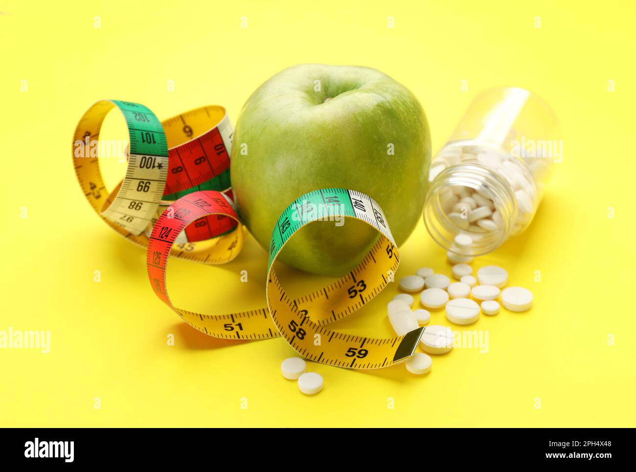 Pilules de perte de poids, pomme et ruban de mesure sur fond jaune Photo  Stock - Alamy