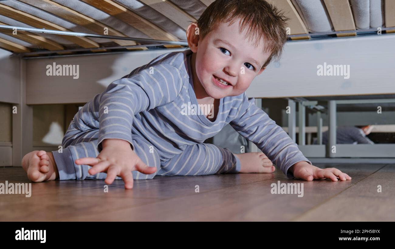 Bébé rampant et se cache sous le lit. Un enfant a grimpé sous le canapé et s