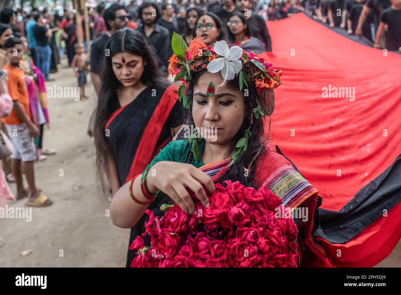 Prachyanat École d'artistes en action et en design marche avec une bannière lors d'une représentation de Lal Jatra (procession rouge) sur le campus de l'Université de Dhaka. L'école d'action et de conception de Prachyanat a organisé une procession de Lal Jatra (procession rouge), pour se rappeler le génocide commis par l'armée pakistanaise à 25 mars 1971 à Dhaka, au Bangladesh, sur 25 mars 2023. En cette nuit noire de l'histoire nationale, les dirigeants militaires pakistanais ont lancé « l'opération Searchlight », tuant quelques milliers de personnes dans la seule répression de cette nuit-là. Dans le cadre de l'opération, des chars ont été déployés à partir du cantonnement de Dhaka et une ville endormie s'est réveillée Banque D'Images