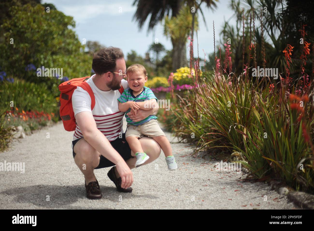 Père et bébé assis dans un beau jardin Banque D'Images