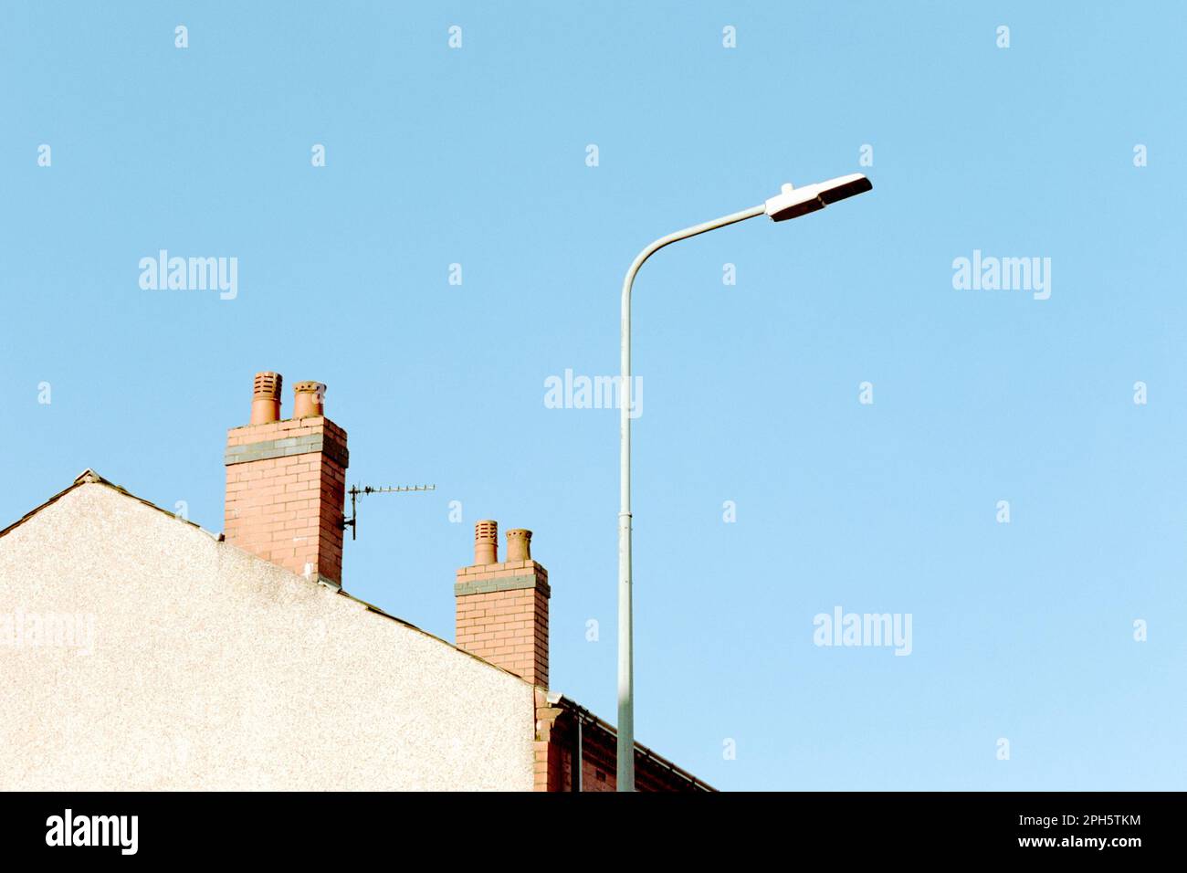 Lampadaire de rue et deux pots de cheminée sur une maison de terrasse d'extrémité dans une rue britannique typique un matin ensoleillé avec ciel bleu clair. Minimaliste, abstrait Banque D'Images