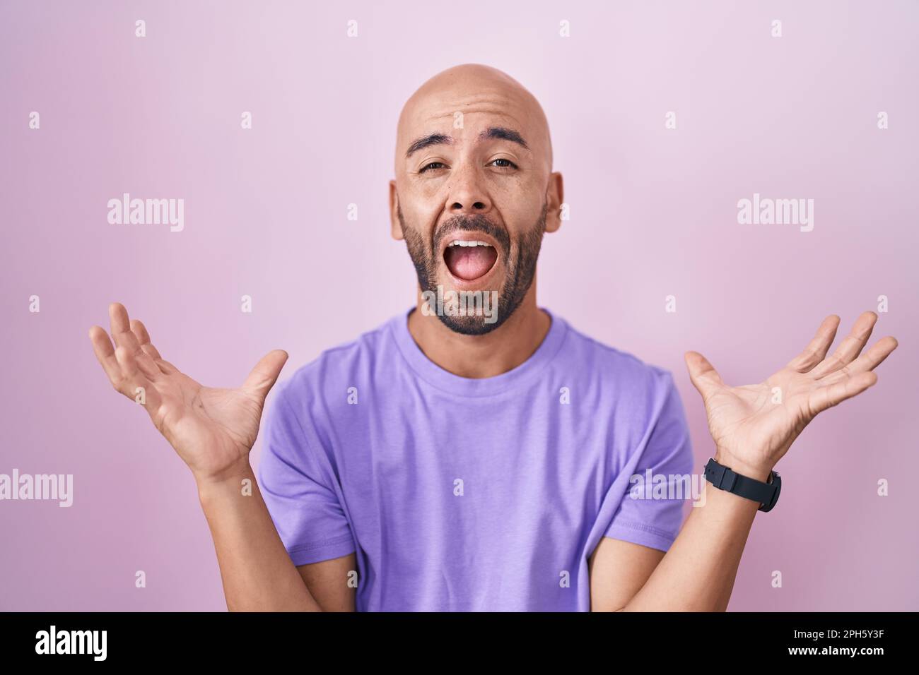 Homme chauve d'âge moyen debout sur fond rose célébrant fou et fou pour le succès avec les bras levés et les yeux fermés criant excités. prix du gagnant Banque D'Images