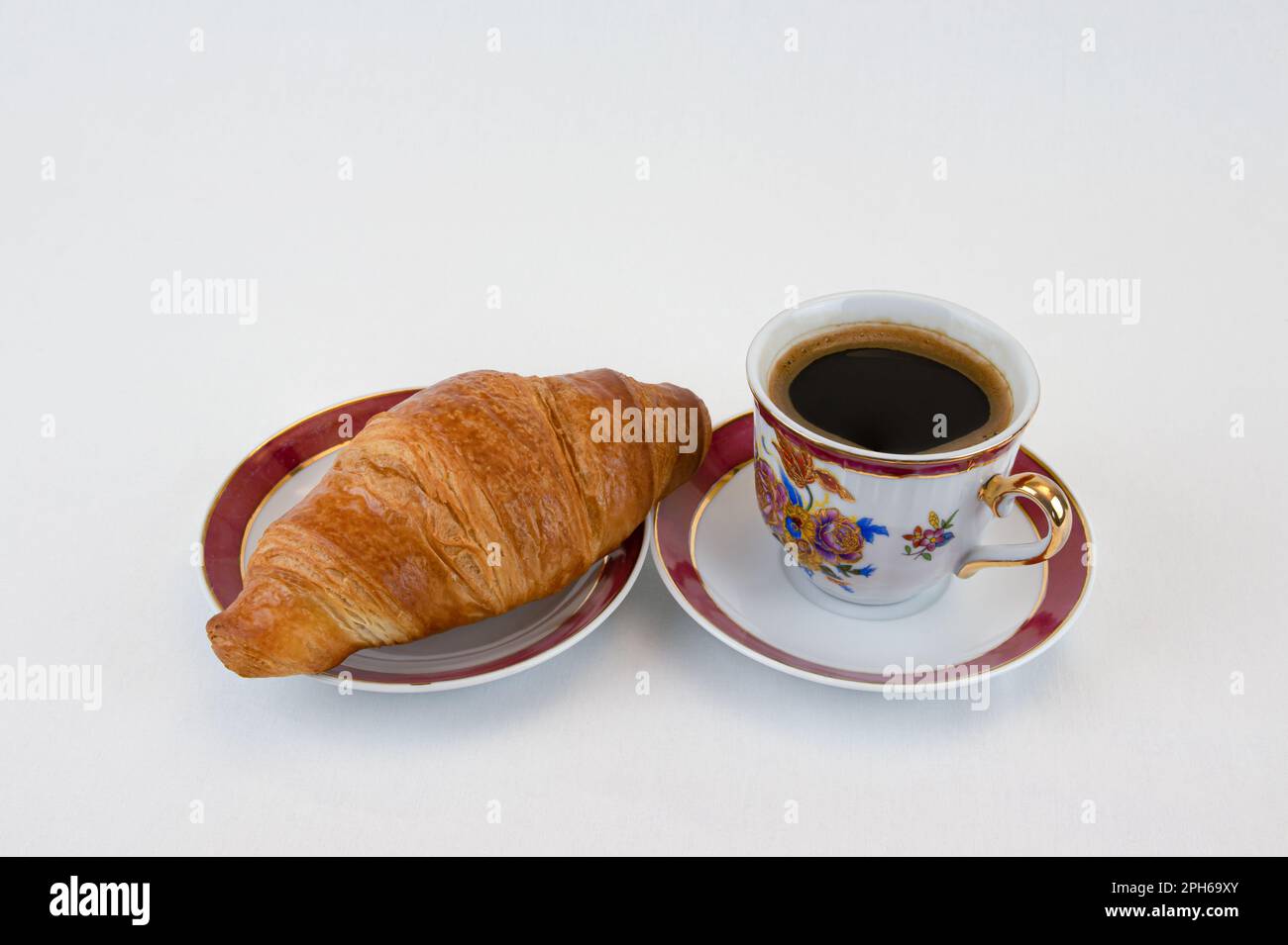 Croissant sur fond de grains de café gros plan. Banque D'Images