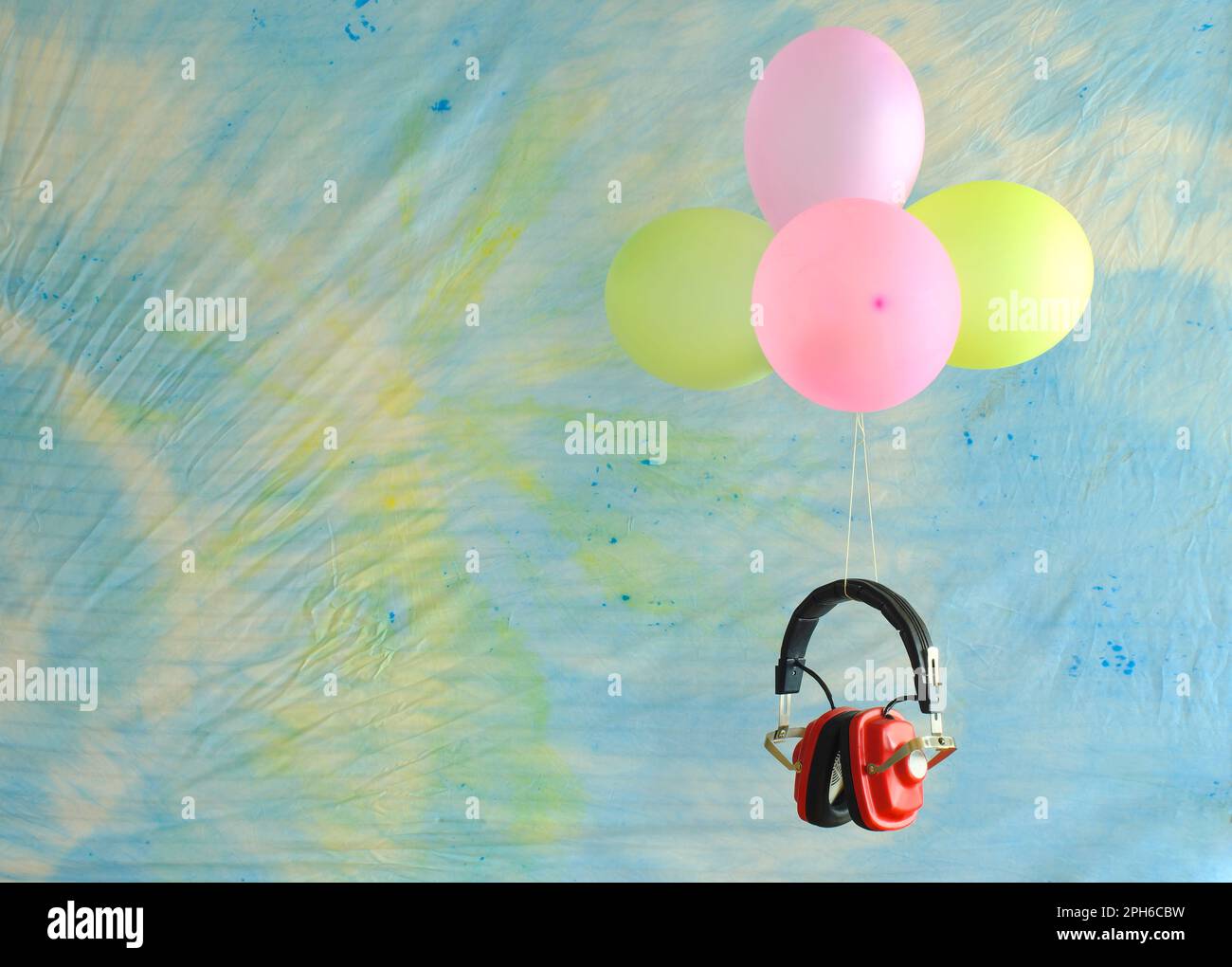 Casque rouge vintage et ballons flottant sur fond de tissu batik, podcasting, musique, concept d'inspration. Espace de copie libre. Banque D'Images