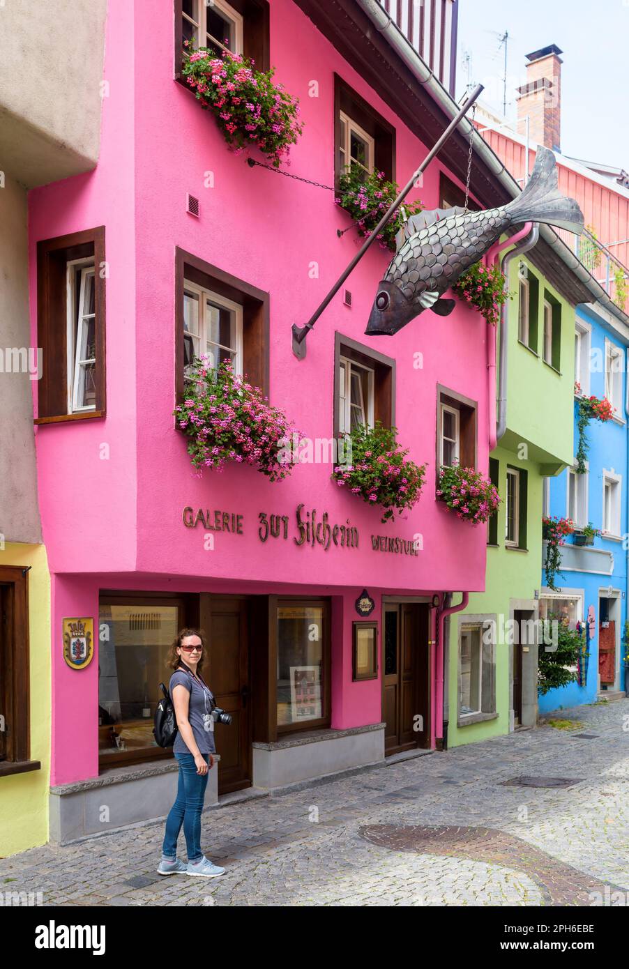 Lindau, Allemagne - 19 juillet 2019: Rue avec des maisons colorées dans la vieille ville de Lindau, la femme touristique marche dans l'allée en passant par le restaurant de poissons en été. Elles Banque D'Images