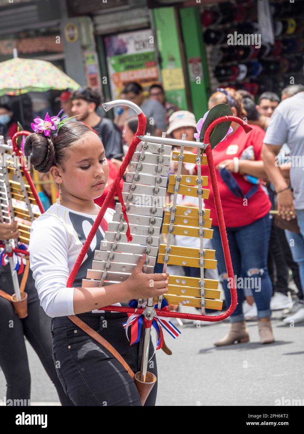 Jeune fille dans un défilé de l'indépendance du Costa Rica jouant une cloche verticale lyre. Banque D'Images