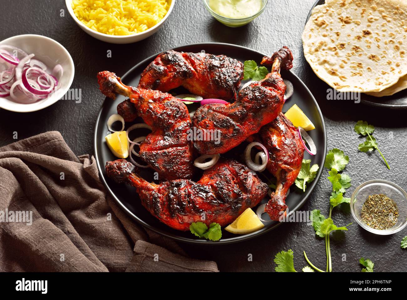 Poulet tandoori de style indien sur plaque sur fond de pierre sombre. Cuisses de poulet marinées au yaourt et aux épices. Vue rapprochée Banque D'Images