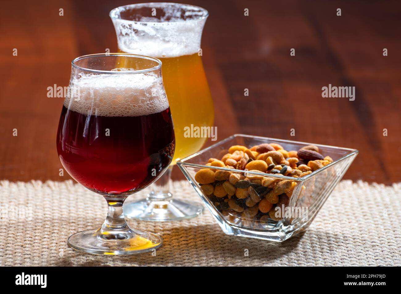 Verres de bière blonde jaune belge et marron foncé faits à l'abbaye servis au bar avec noix de fête, gros plan Banque D'Images