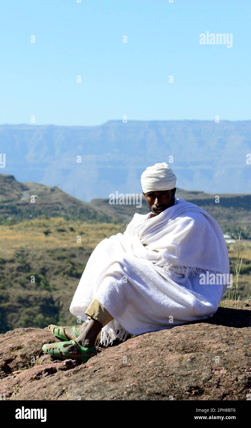 Un prêtre orthodoxe éthiopien assis au-dessus d'une église Rock-hewn à Lalibela, en Éthiopie. Banque D'Images