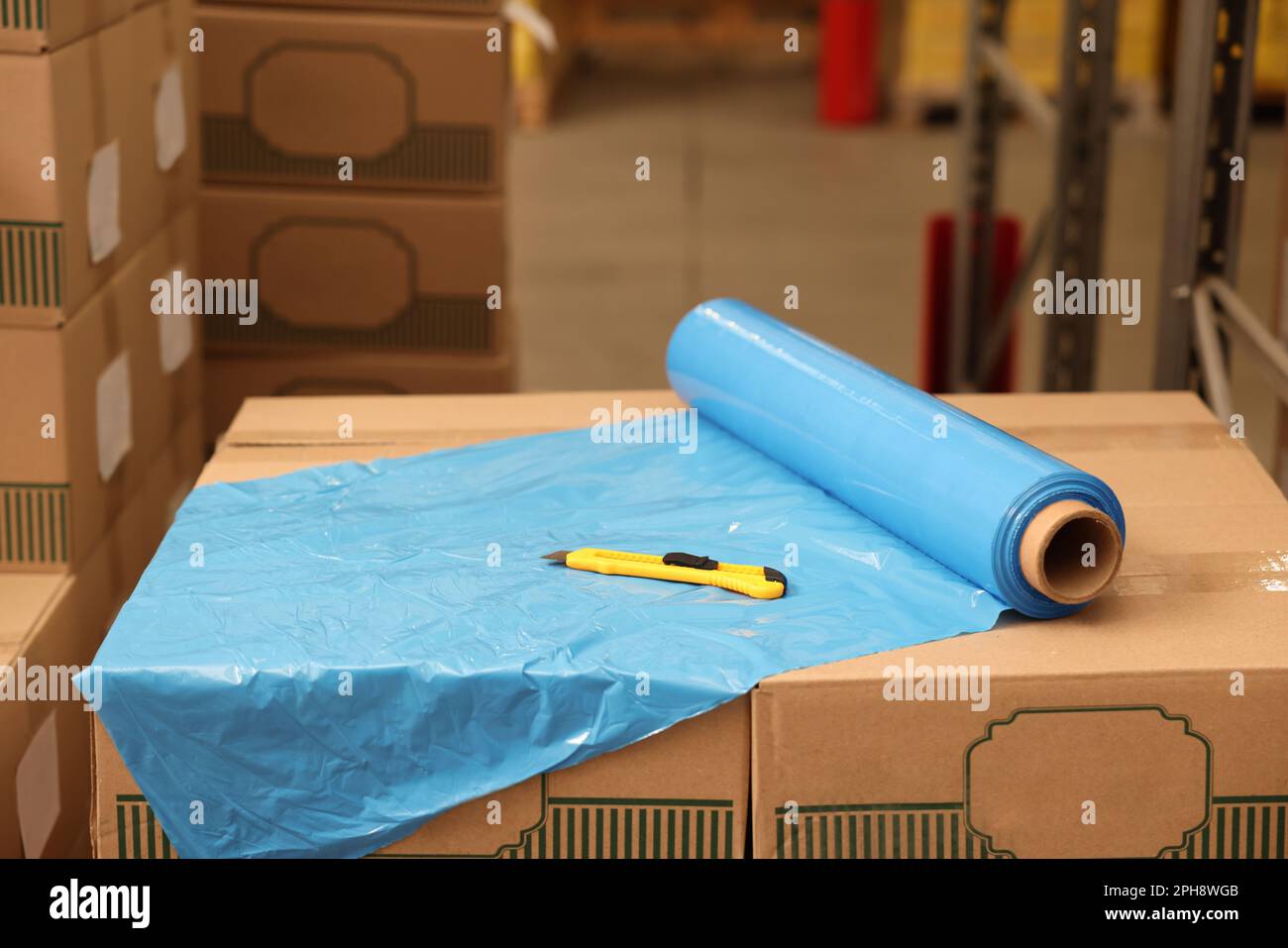 Rouleau de papier d'emballage extensible et couteau utilitaire sur les boîtes dans l'entrepôt Banque D'Images