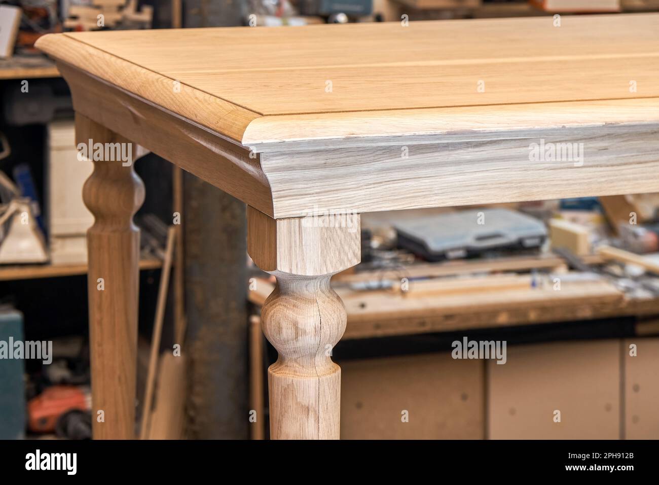 Table à manger en bois avec jambe sculptée en chêne massif et cadre en métal en vue rapprochée de l'atelier Banque D'Images