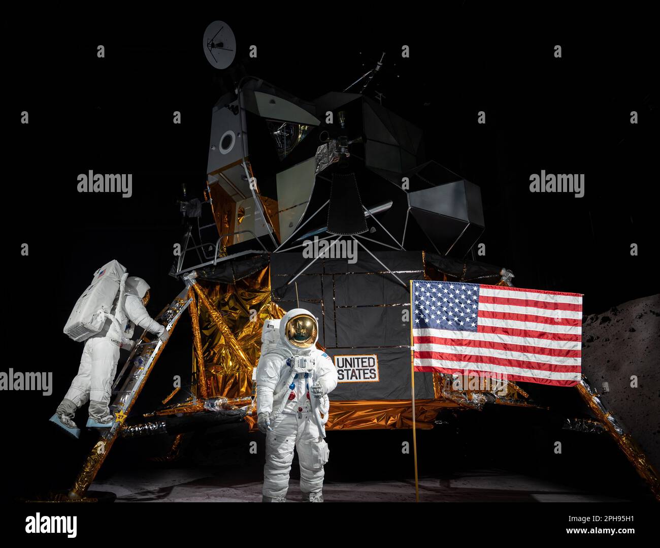 Deux astronautes se tenant côte à côte dans leurs combinaisons spatiales avec le drapeau américain, fermement plantés dans le sol derrière eux Banque D'Images