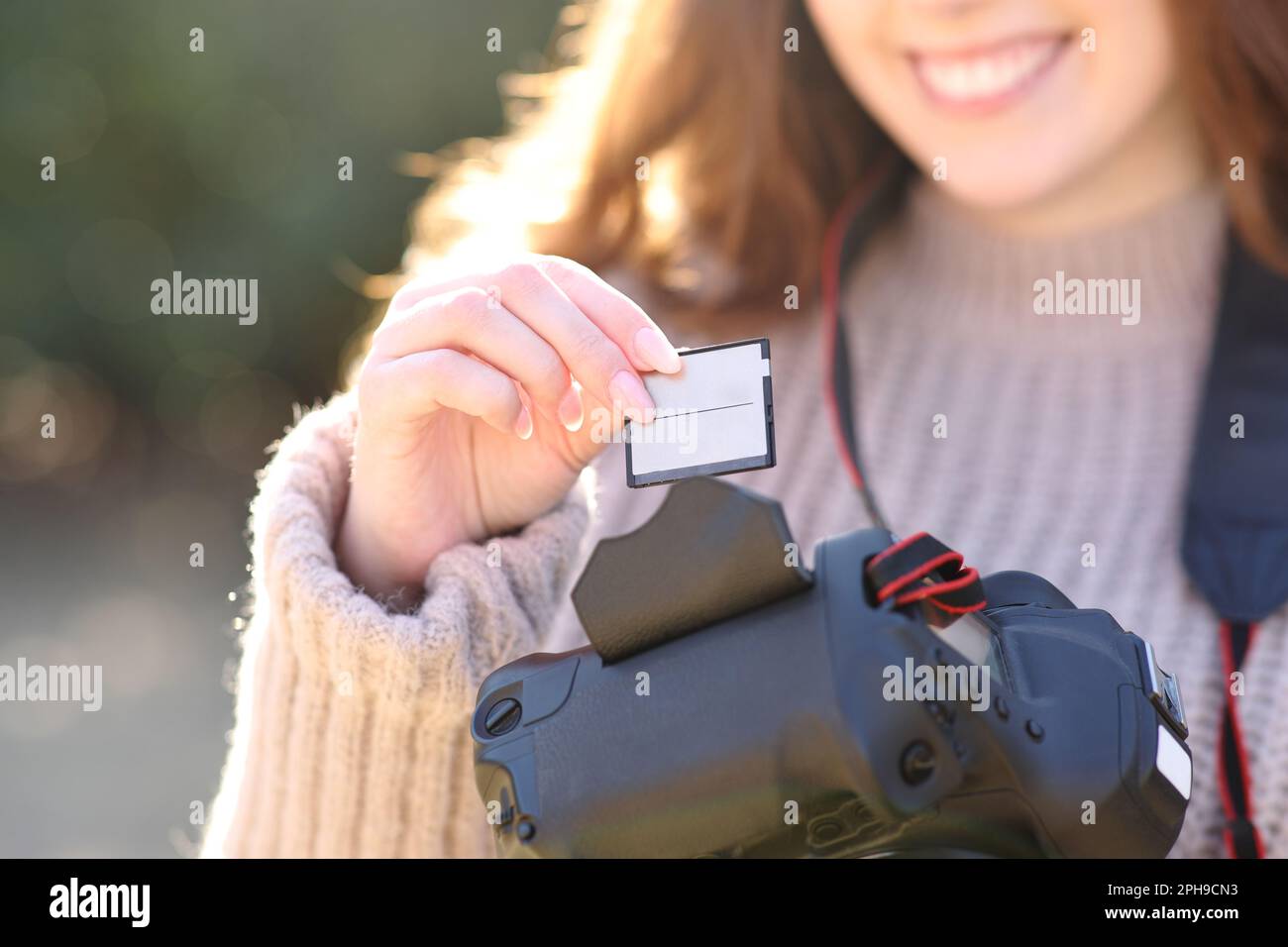 Gros plan sur un photographe insérant une carte dans un appareil photo reflex numérique en hiver Banque D'Images