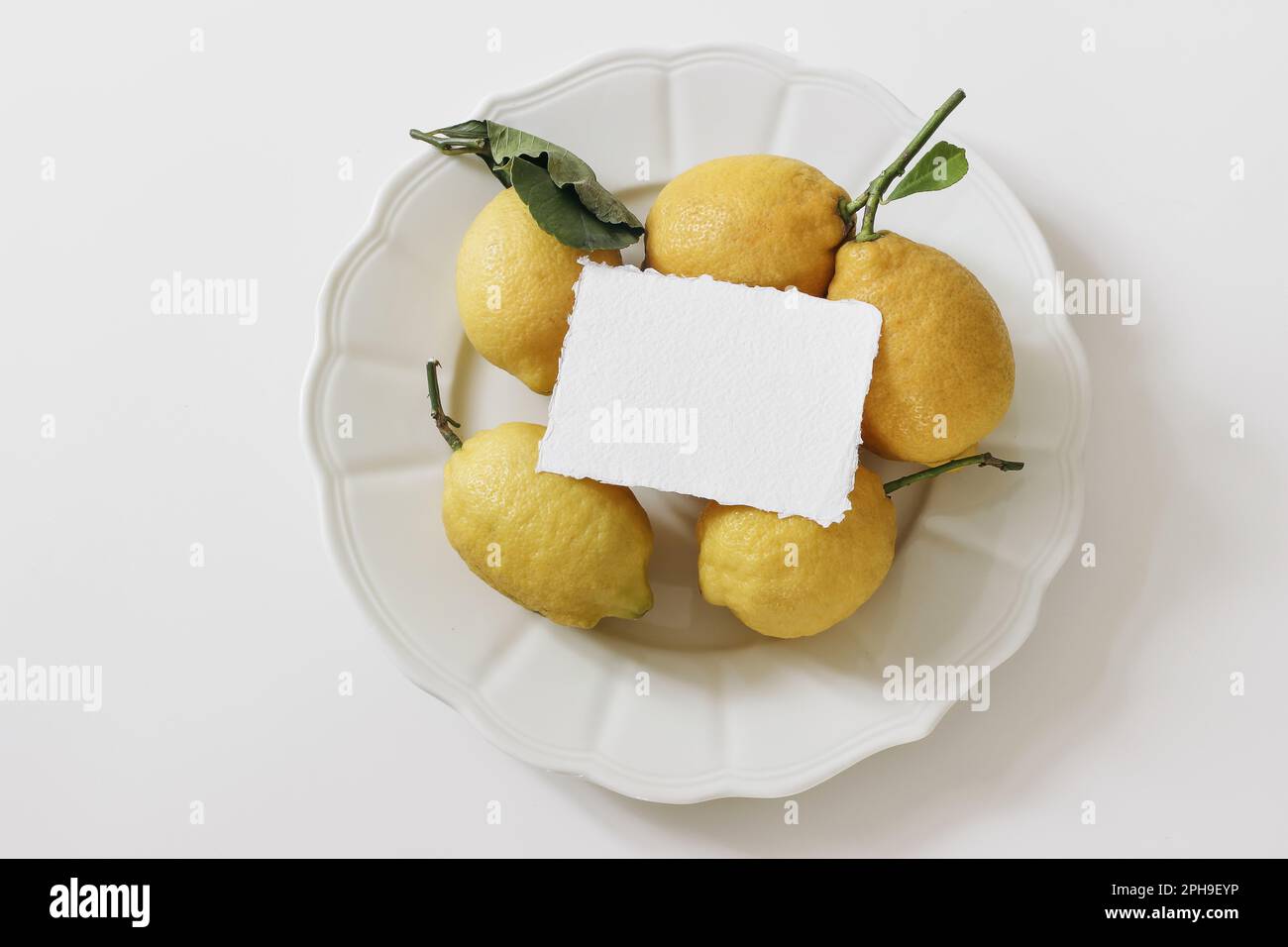 La nourriture d'été reste vie. Citrons jaunes sur plaque céramique isolés sur fond blanc de table. Maquette de carte en coton vierge. Gros plan sur les produits frais méditerranéens Banque D'Images