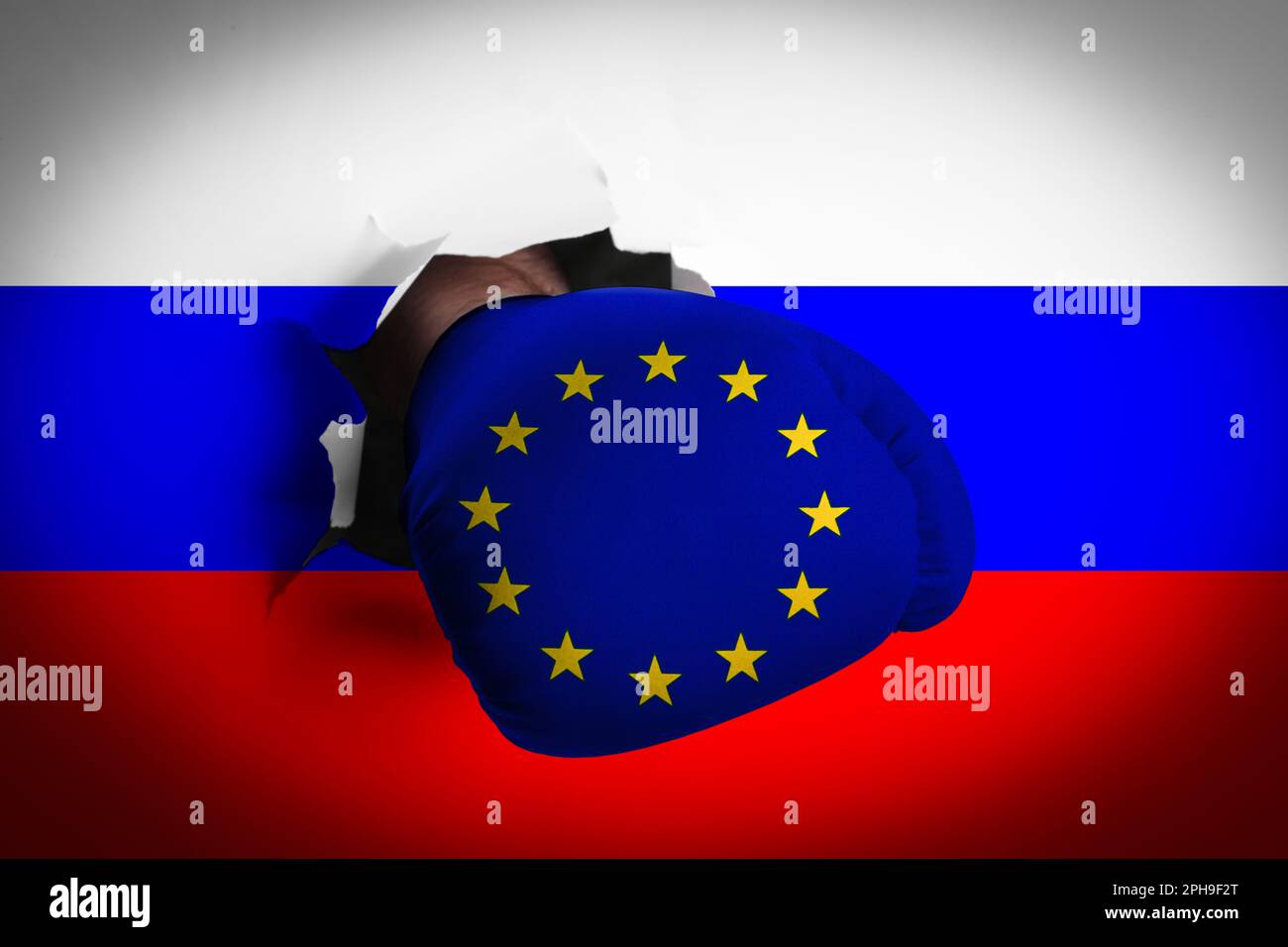 Homme dans le gant de boxe avec les étoiles de l'Union européenne perforant trou à travers le drapeau russe, gros plan. Querelle politique Banque D'Images