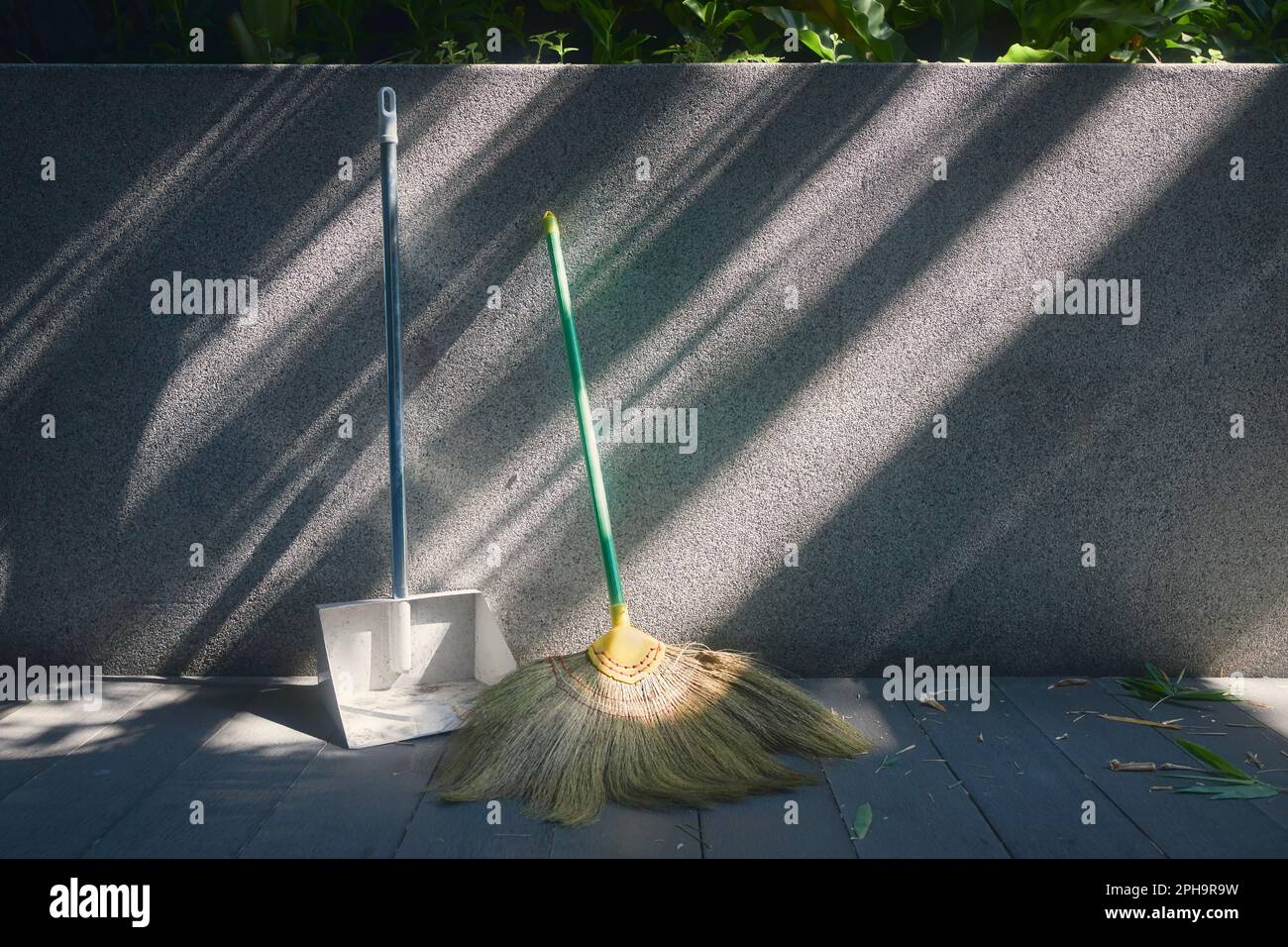 Outils de nettoyage de jardin. Balai et pelle inclinés contre le mur. Banque D'Images