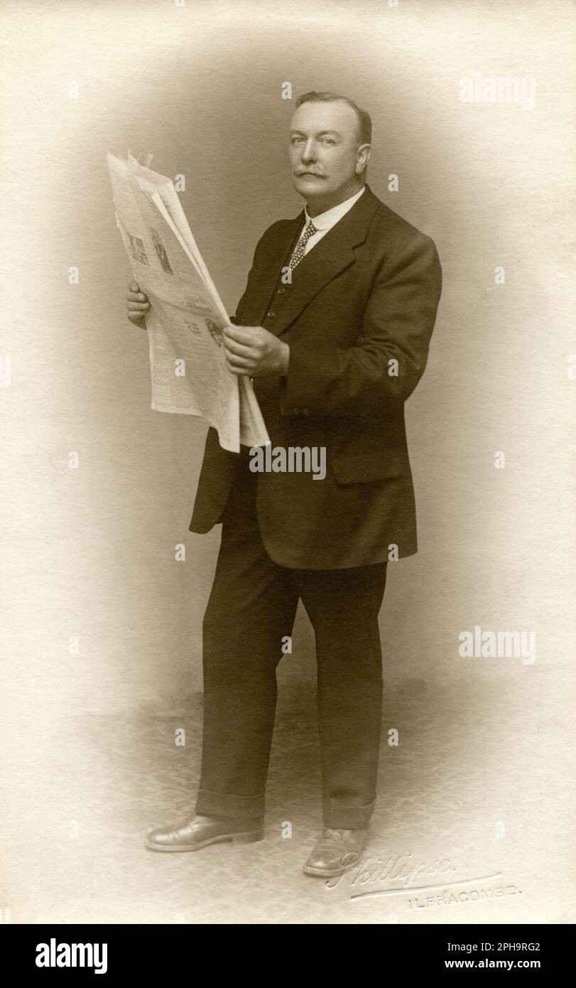 Devon, Angleterre. 1920s. Photographie de portrait d'un homme élégant et distingué posant avec un journal. Prise par le photographe Ernest George Phillipse de 12 Promenade, Ilfracombe, Devon. Banque D'Images