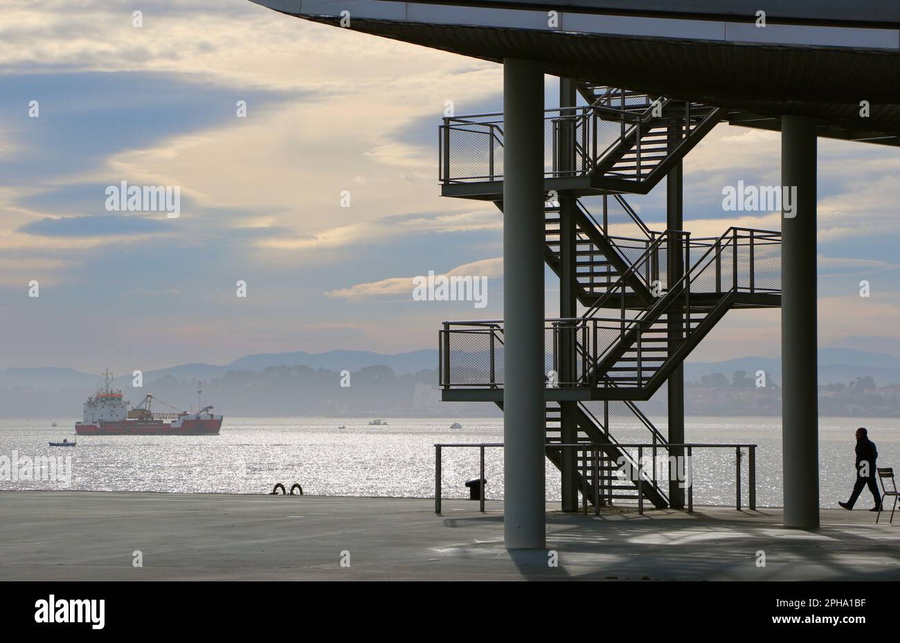 Personne marchant avec le bateau de dragage Omvac Cinco en passant par le centre des arts de Botin à côté de la baie de Santander Cantabria Espagne, le matin du printemps Banque D'Images