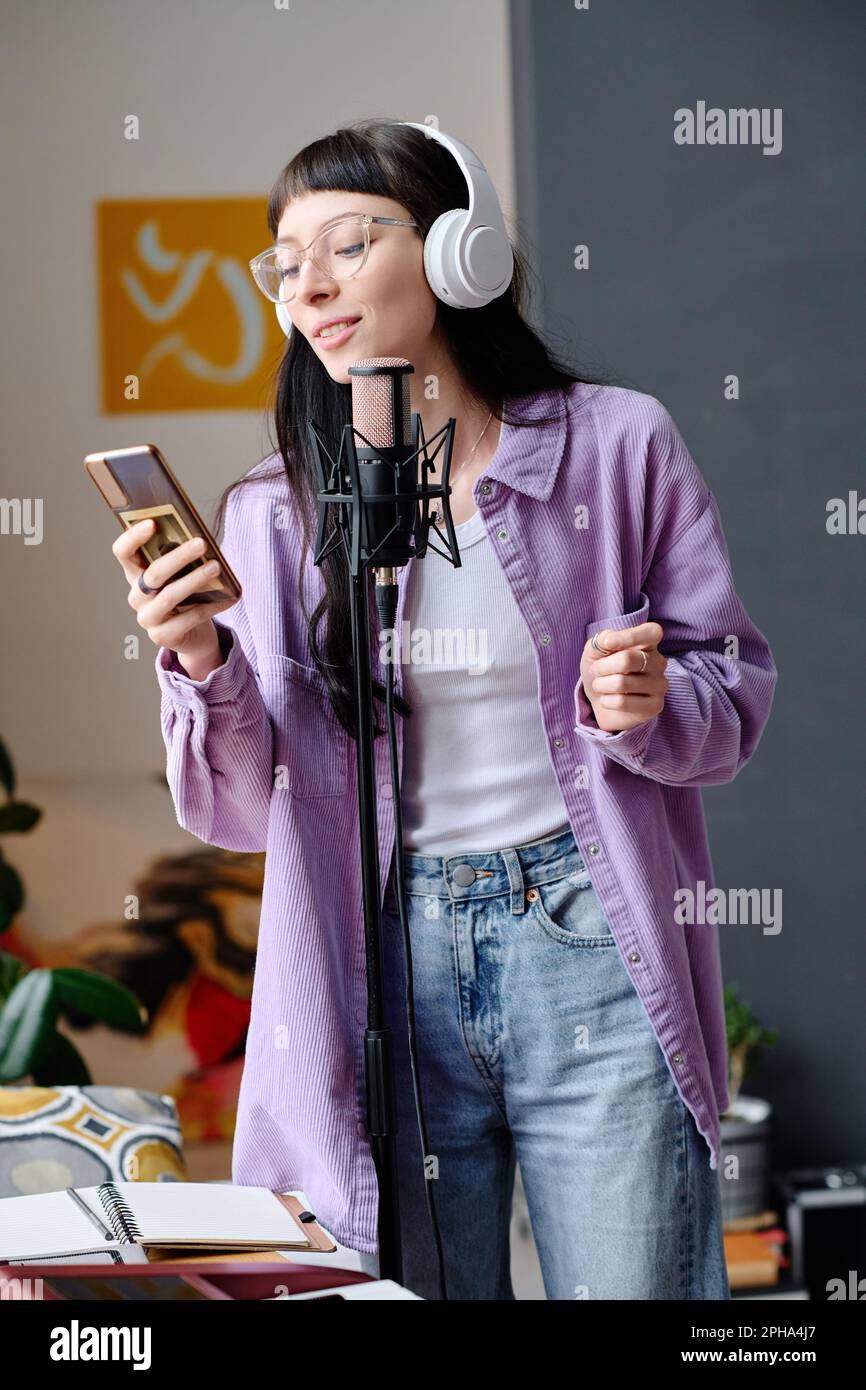 Jeune femme dans un casque utilisant son smartphone pour chanter des  chansons dans le microphone Photo Stock - Alamy