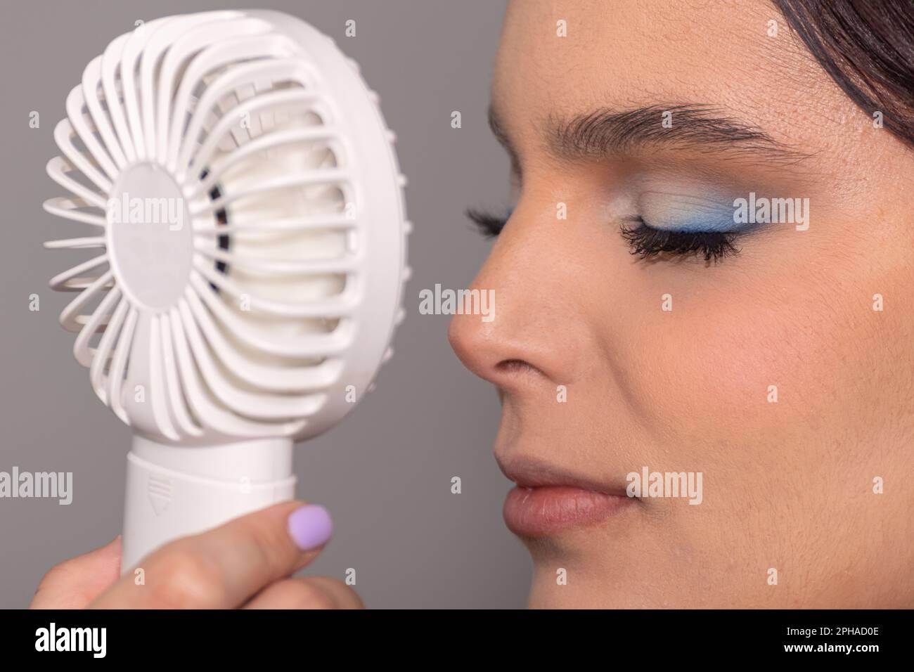 Une jeune femme se rafraîchit avec un petit ventilateur à main lors d'une chaude journée d'été Banque D'Images