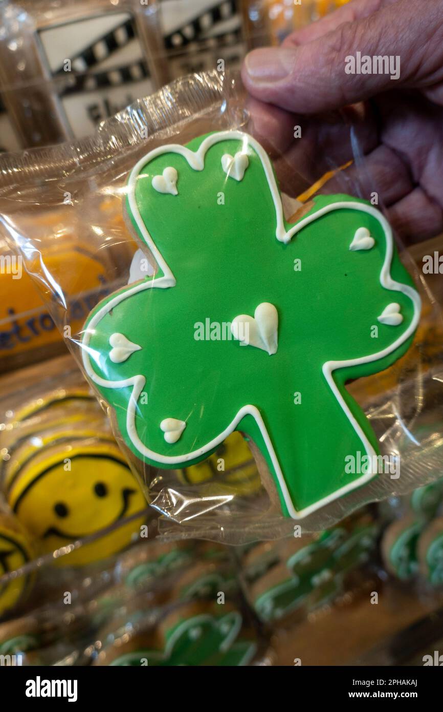 Un client tient un biscuit en forme de Shamrock pour bonne chance près de Saint Patrick Day, Grand Central, Market, 2023, New York City, ÉTATS-UNIS Banque D'Images