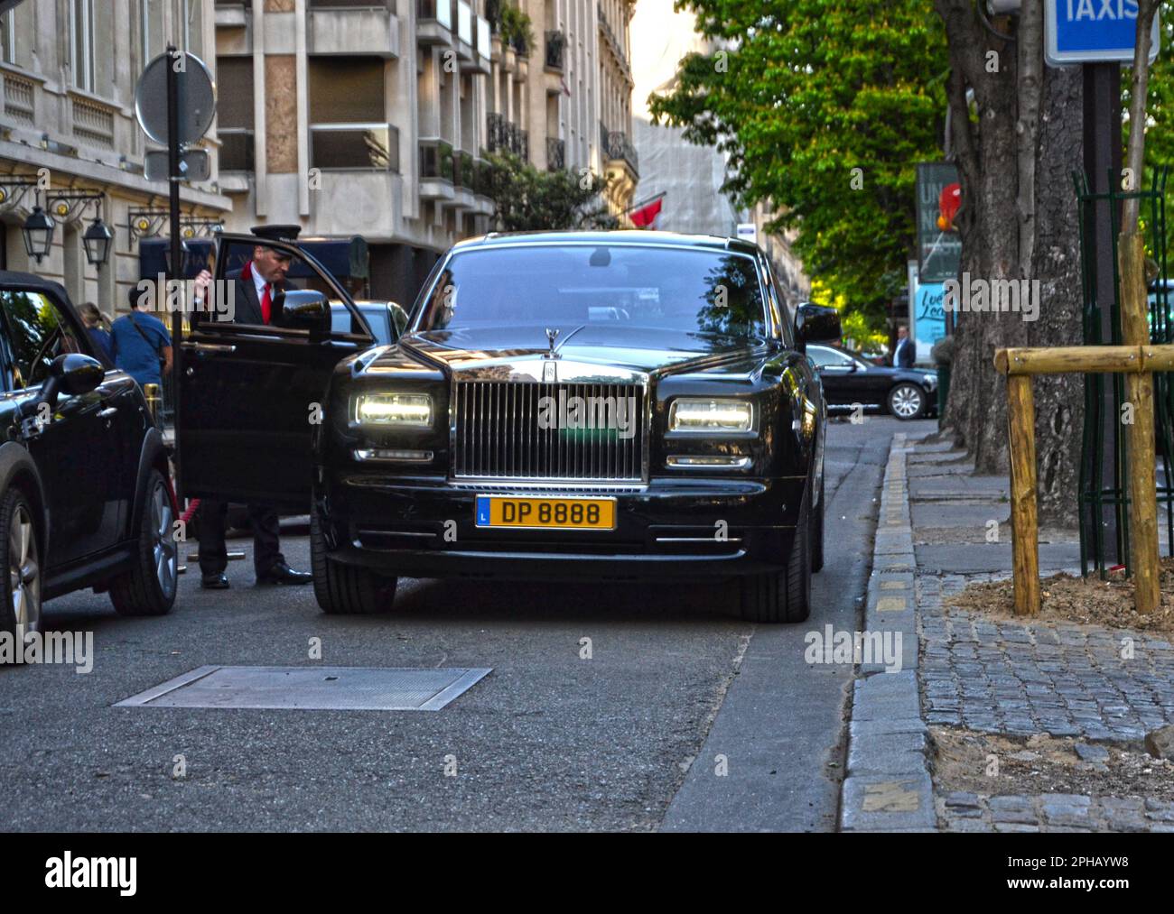 Paris, France - 18 avril 2015 : fantôme de la royce des Rolls noirs garés dans une rue, dans le quartier de George V. Un employé d'un palais ouvre la porte à la cus Banque D'Images