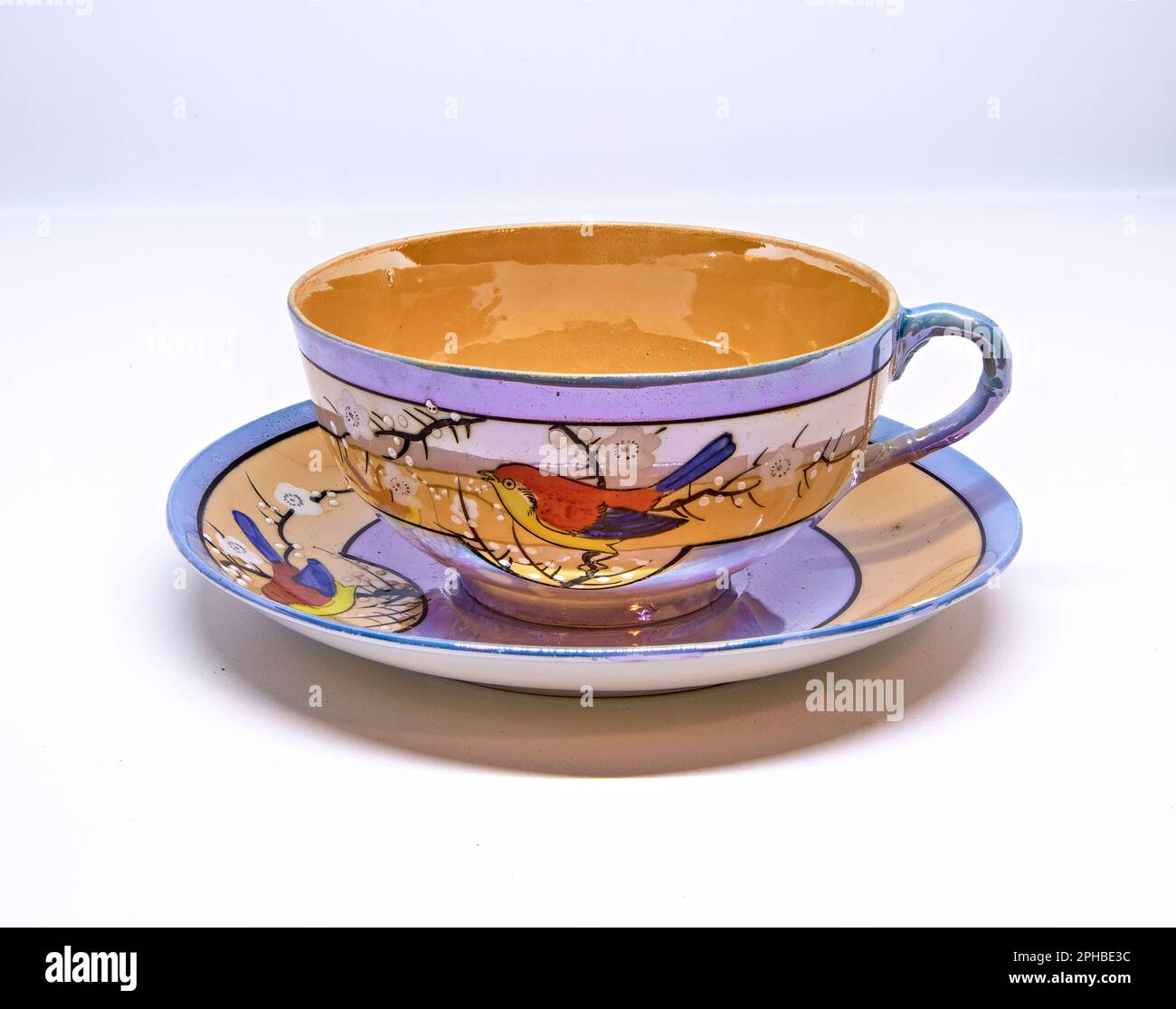 Tasse de thé et soucoupe antiques sur fond blanc.fabriqué au Japon. Avec un oiseau rouge, jaune et bleu. Banque D'Images