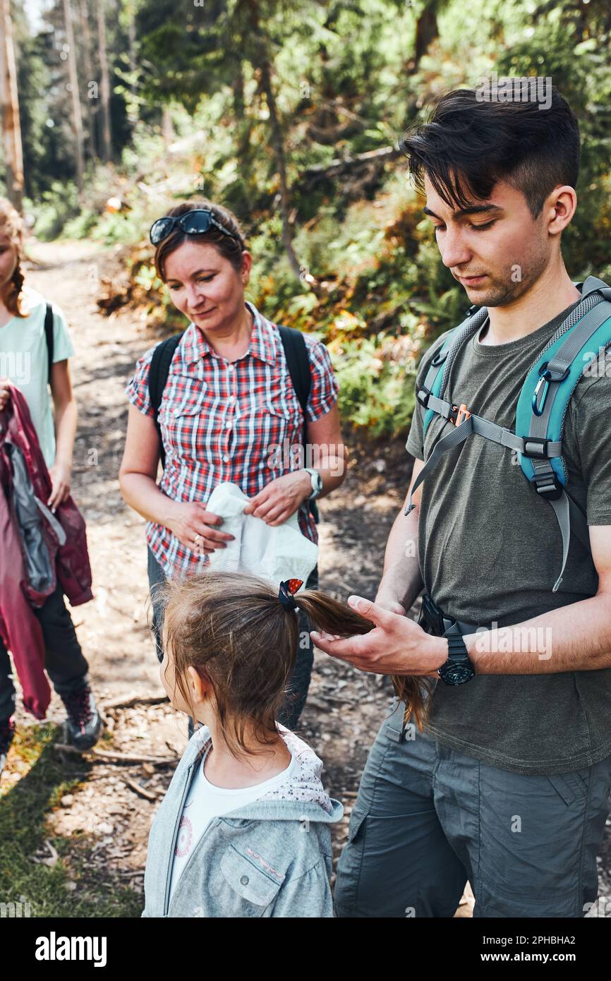 Famille avec des sacs à dos randonnée dans une montagne passer des vacances d'été ensemble sur le chemin de la forêt parler et admirer la nature de montagne lan Banque D'Images