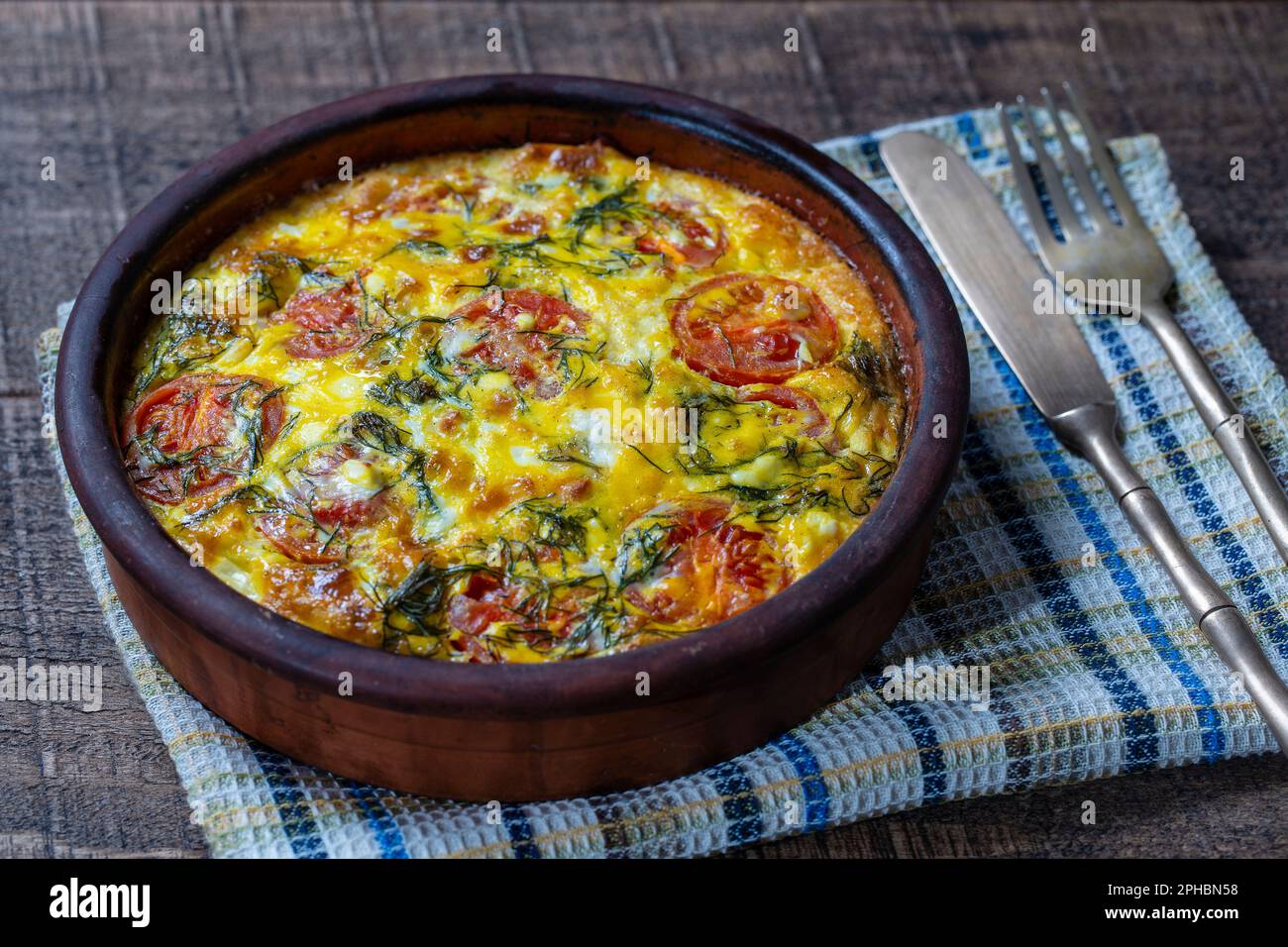 Bol en céramique avec frittata de légumes, simple nourriture végétarienne. Frittata avec oeuf, tomate, poivre, oignon, aneth vert et fromage sur table en bois, fermer u Banque D'Images