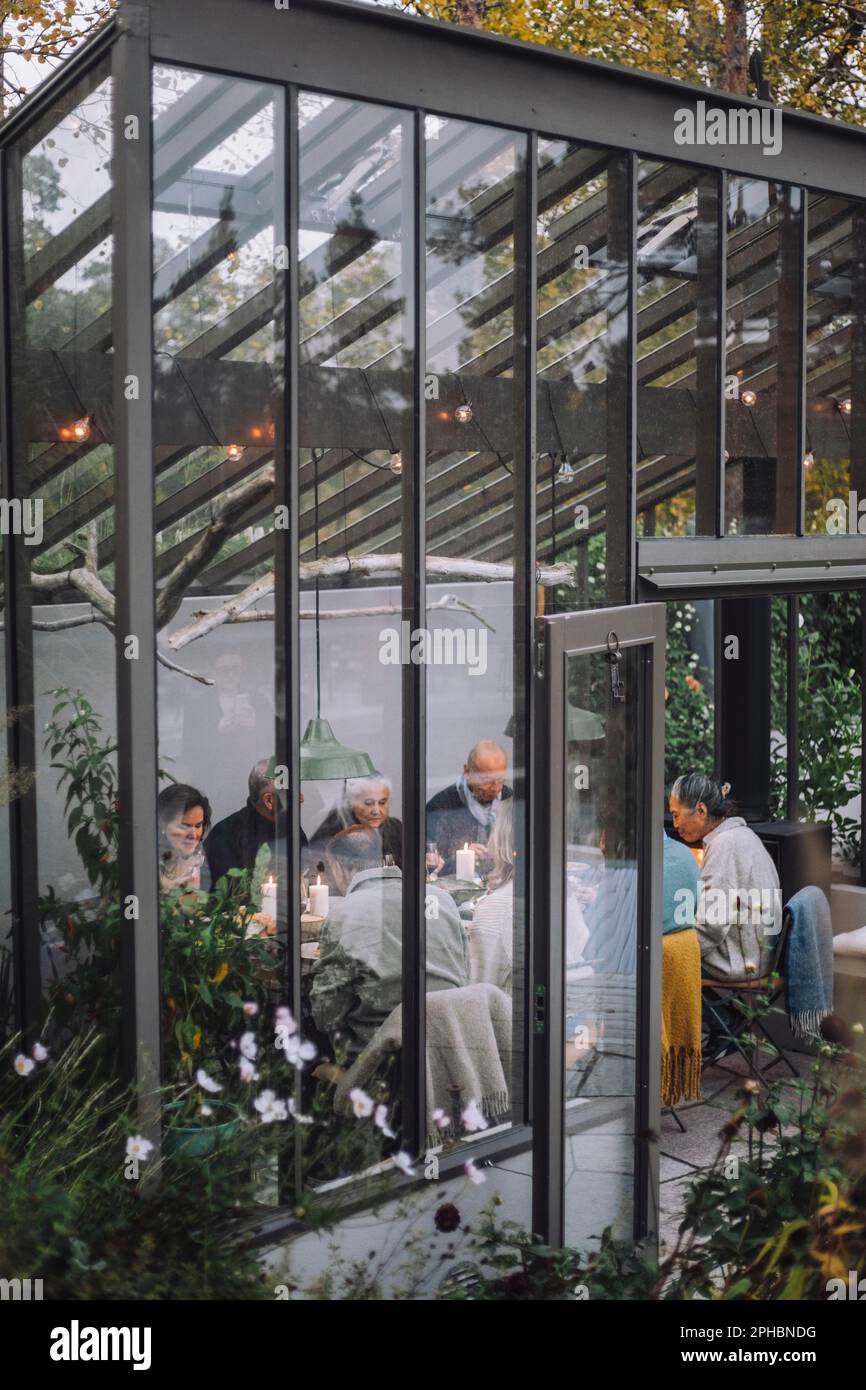Des amis à la retraite, hommes et femmes, qui ont de la nourriture les uns avec les autres pendant le dîner dans l'arrière-cour Banque D'Images