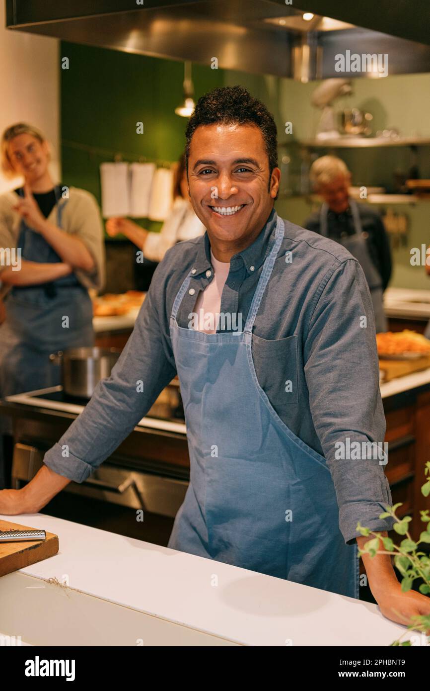 Portrait d'un étudiant de sexe mûr heureux debout dans la cuisine pendant le cours de cuisine Banque D'Images