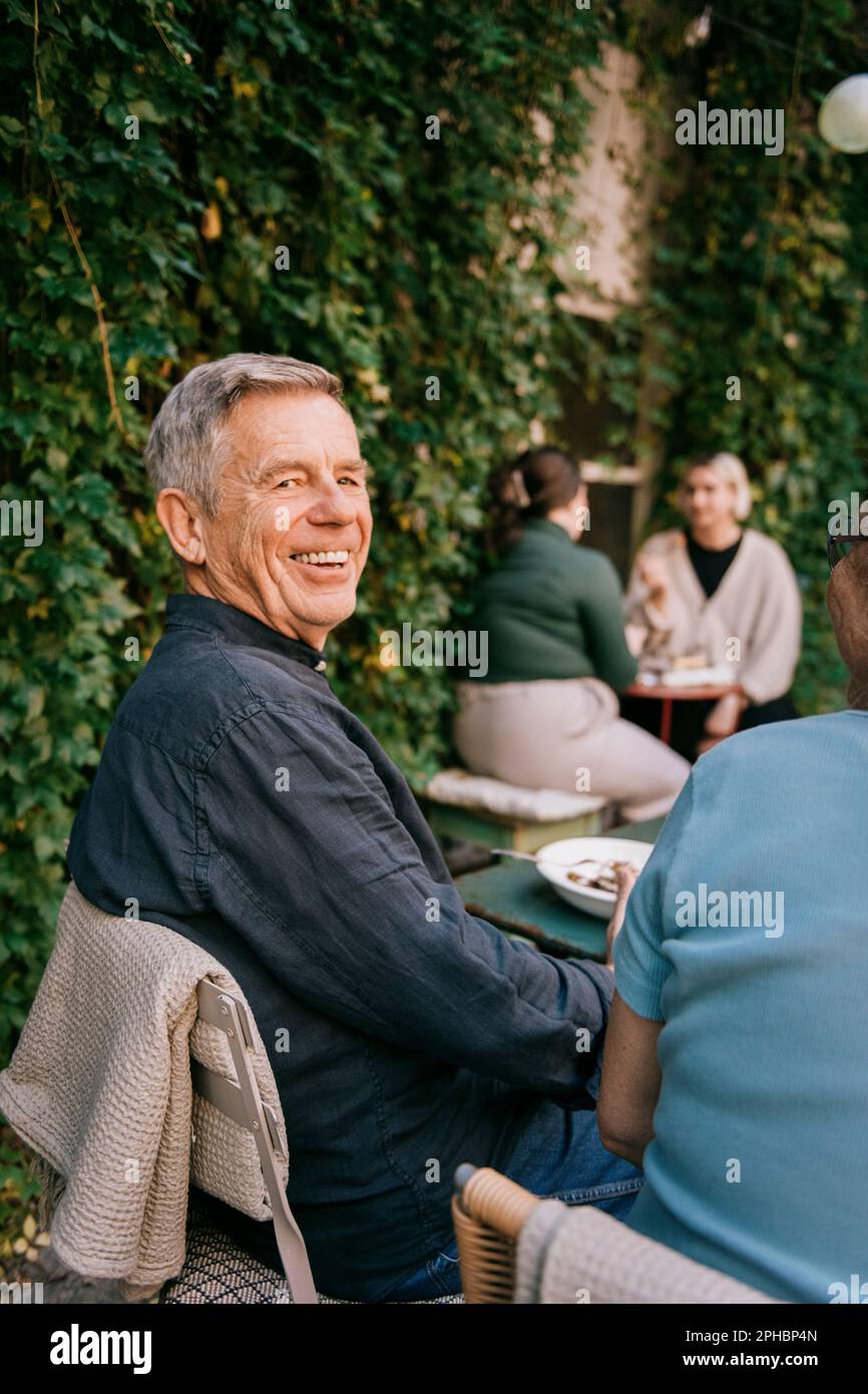 Joyeux homme senior assis sur une chaise au restaurant Banque D'Images