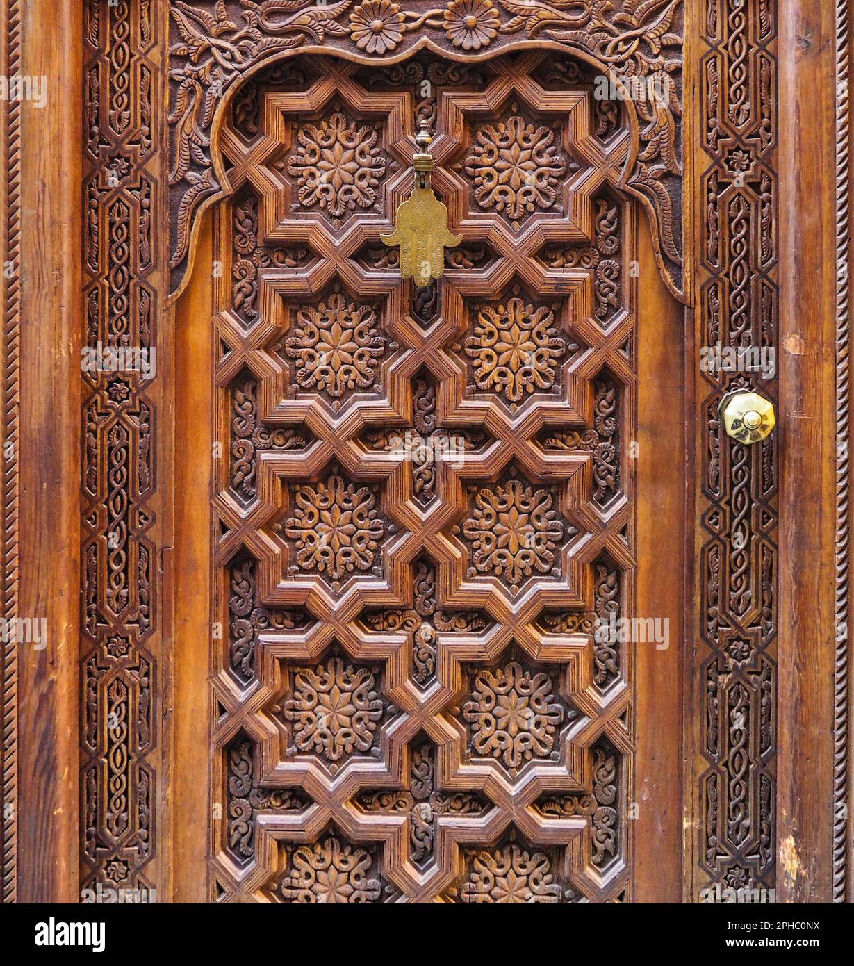 Ancienne porte en bois décorée avec des ornements orientaux typiques du Maroc, hamsa en métal - amulette en forme de paume - accrochée sur le dessus Banque D'Images