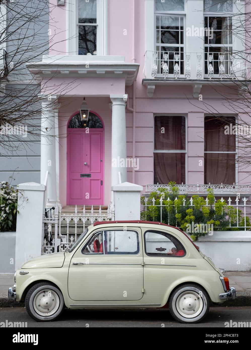 Jolie voiture classique Fiat 500 beige couleur vintage garée en face d'une maison avec une porte rose sur une rue résidentielle de Notting Hill, ouest de Londres Royaume-Uni. Banque D'Images