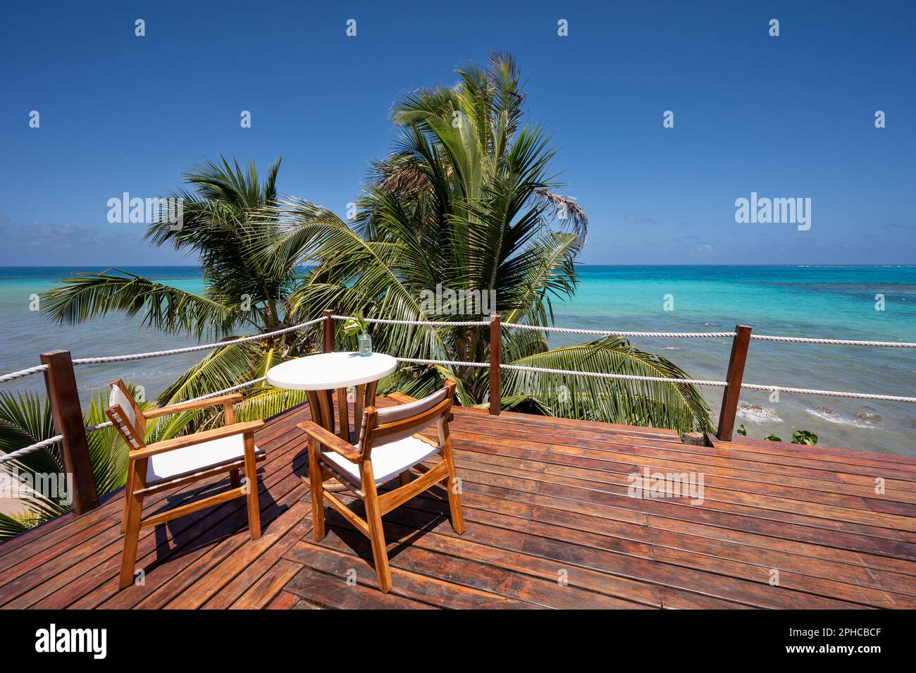 Table de café avec chaise sur fond de mer tropicale. Terrasse en bois vide en bord de mer Banque D'Images