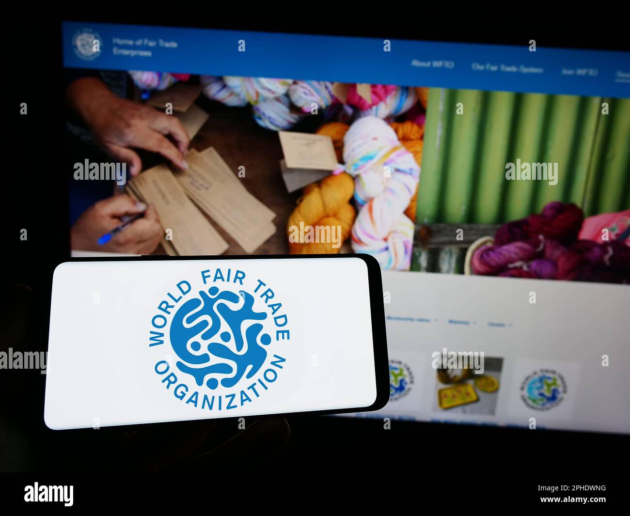 Personne tenant un smartphone avec le logo de l'Organisation mondiale du commerce équitable (WFTO) à l'écran devant le site Web. Mise au point sur l'affichage du téléphone. Banque D'Images Personne tenant un smartphone avec le logo de l'Organisation mondiale du commerce équitable (WFTO) à l'écran devant le site Web. Mise au point sur l'affichage du téléphone. Banque D'Images