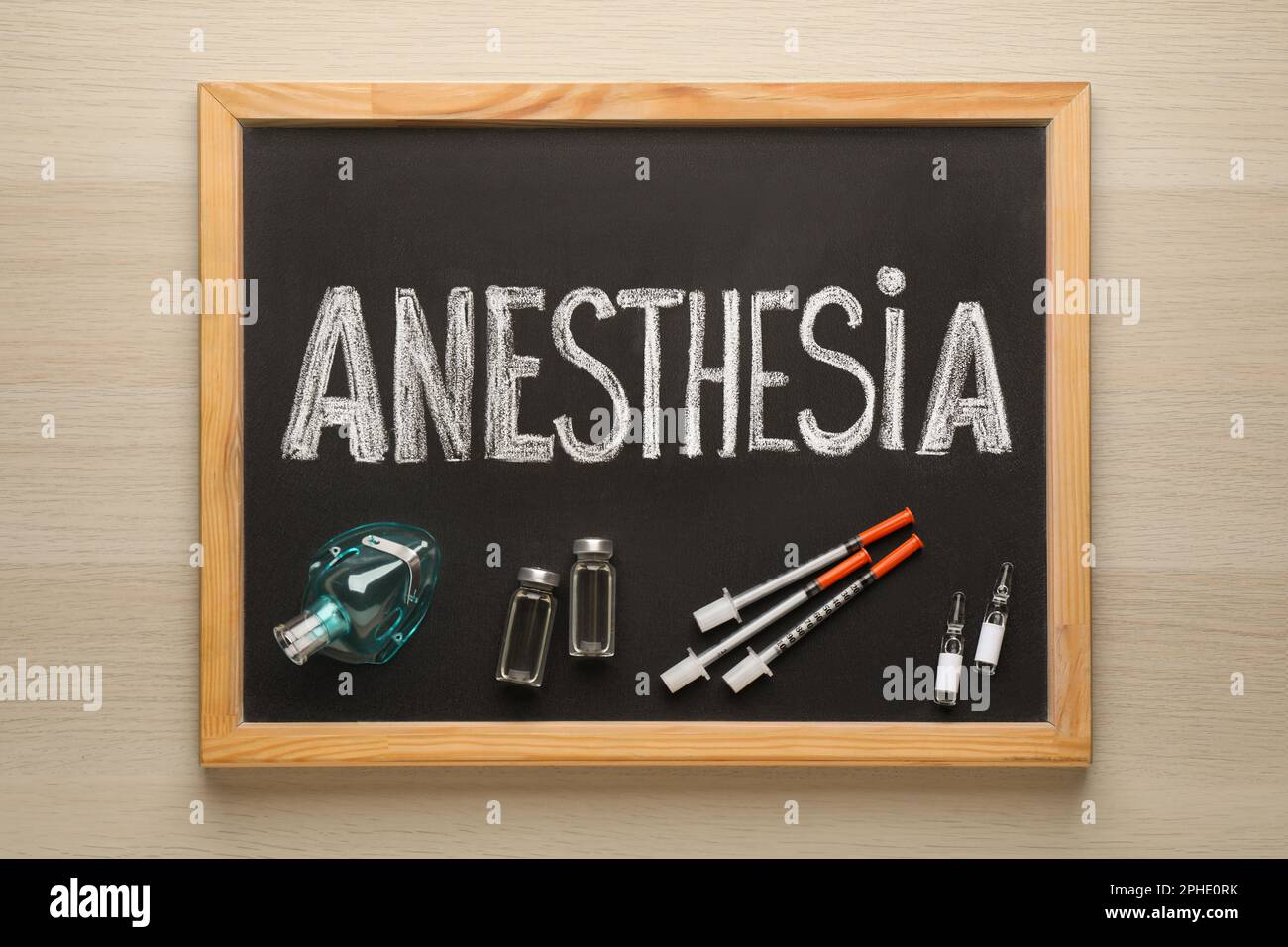 Tableau noir avec anesthésie mot, masque et médicaments sur table en bois, vue de dessus Banque D'Images
