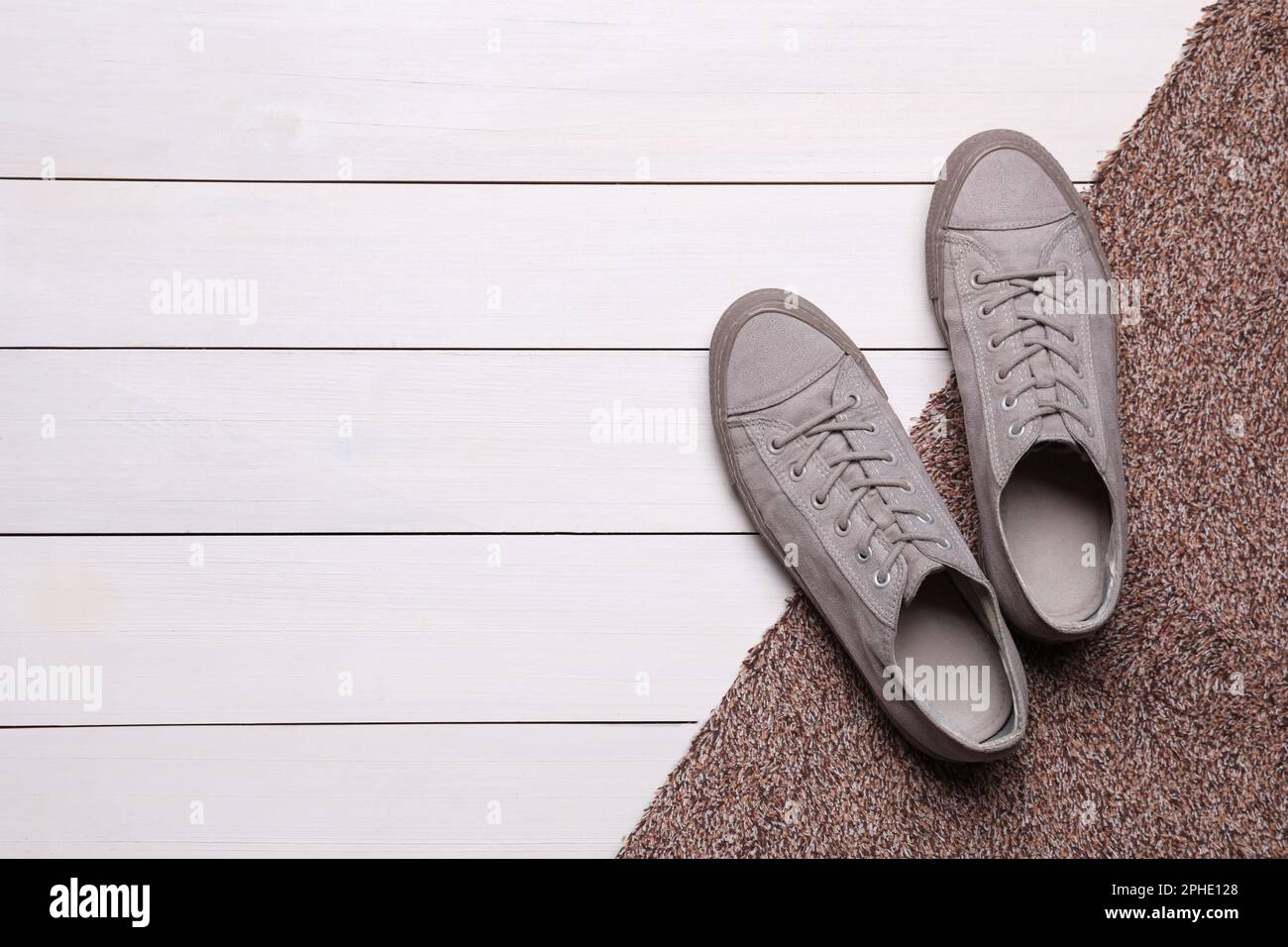 Nouveau tapis de porte propre avec des chaussures sur plancher blanc en bois, plat. Espace pour le texte Banque D'Images