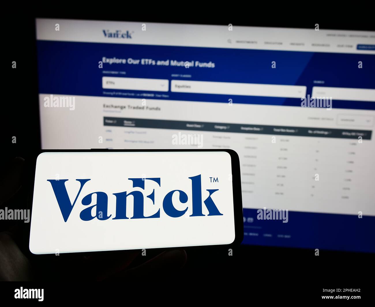 Personne tenant un téléphone mobile avec le logo de la société américaine de gestion d'investissement VanEck sur l'écran en face de la page Web. Mise au point sur l'affichage du téléphone. Banque D'Images