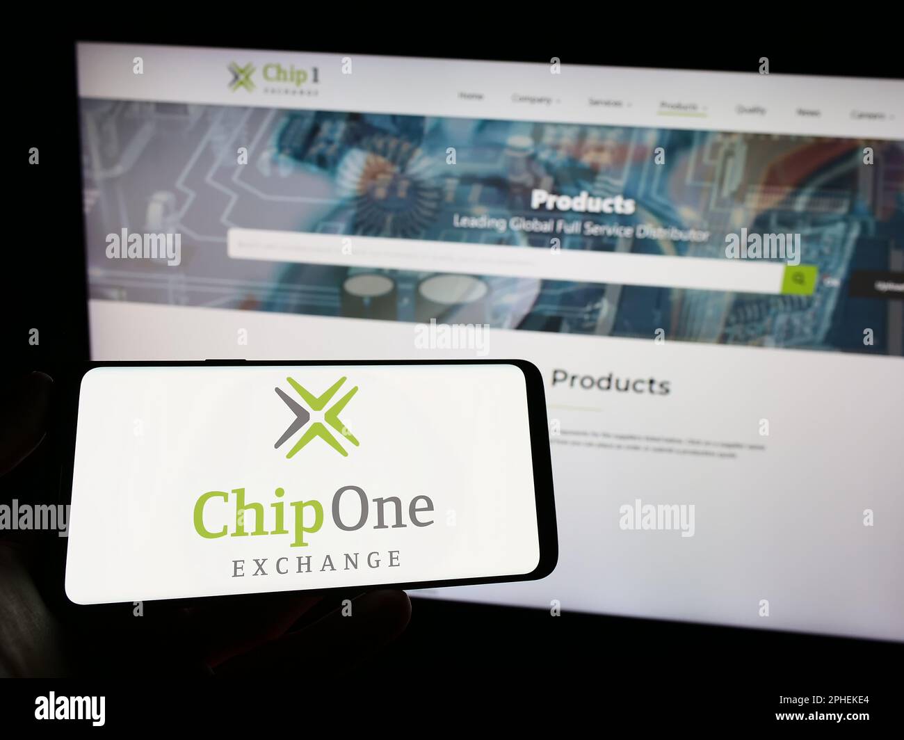 Personne tenant un téléphone portable avec le logo de la société de distribution allemande Chip 1 Exchange à l'écran en face de la page Web d'affaires. Mise au point sur l'affichage du téléphone. Banque D'Images