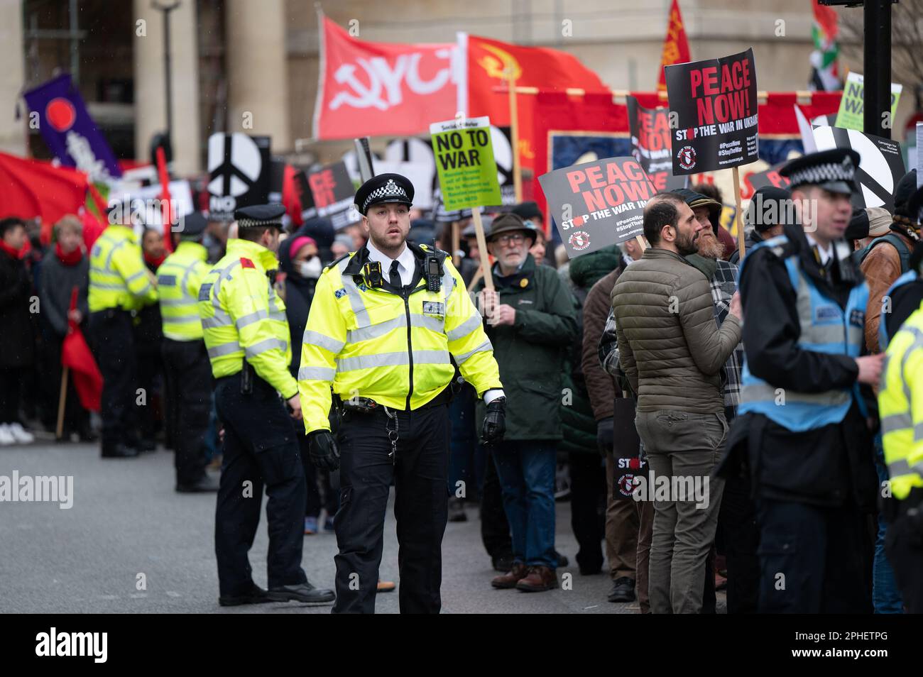 Un groupe de policiers se tenant à côté d'un groupe de personnes protestant contre la guerre en Ukraine Banque D'Images