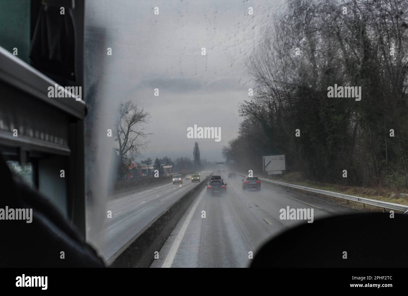 Vue derrière le chauffeur d'autocar, sur le réseau routier français dans les contreforts des Alpes en hiver Banque D'Images